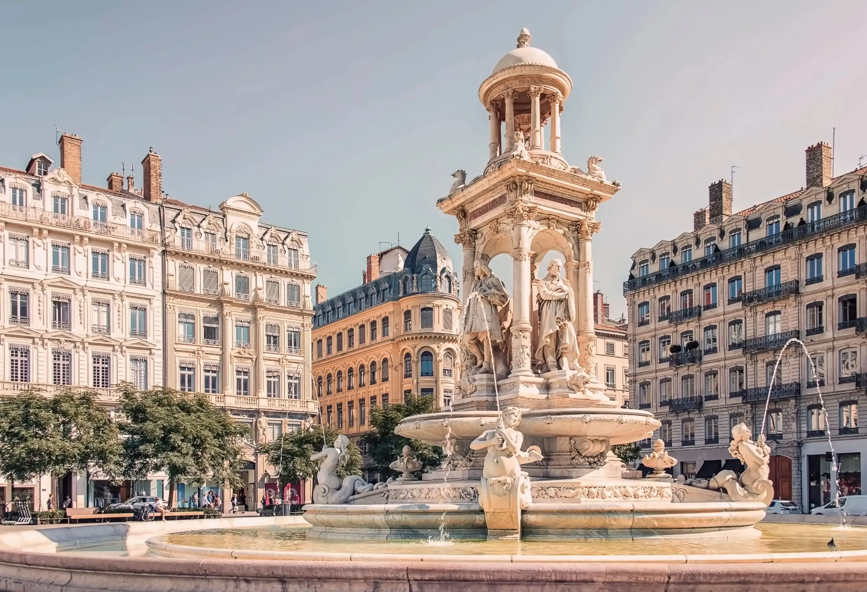 An ornate four-tier fountain with astounding architecture in the background.