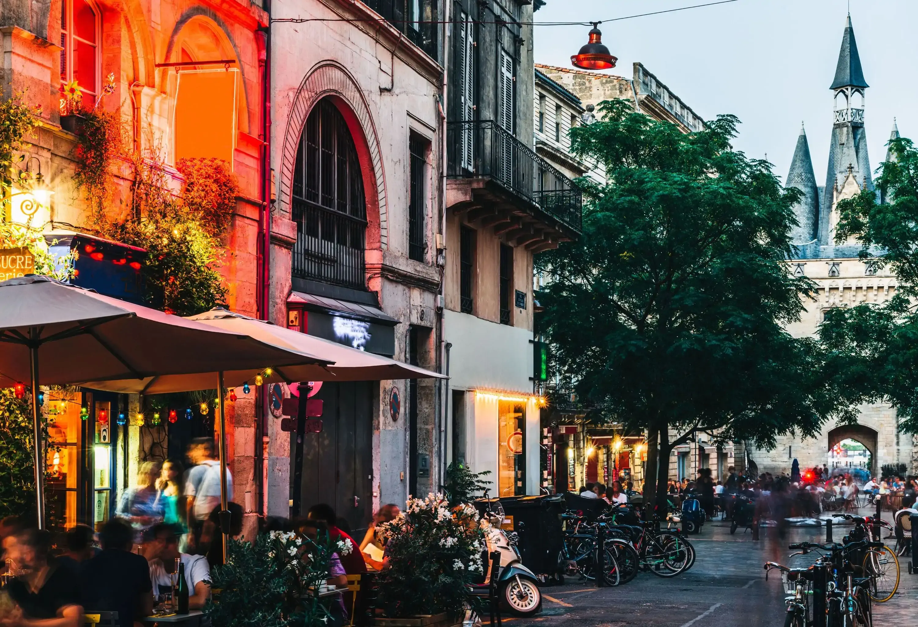 A street lined with parked bicycles and outdoor dining areas beside the illuminated establishments.