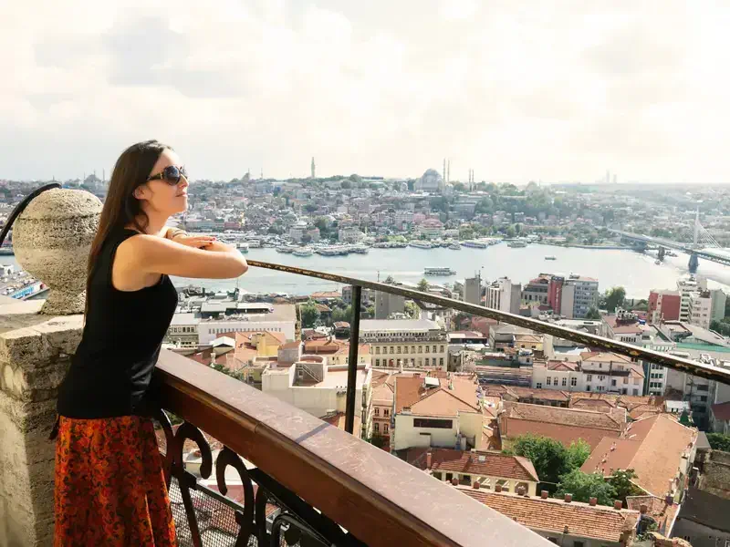 Beautiful woman leaning out the Galata tower enjoying the amazing view of Istanbul, Turkey.
