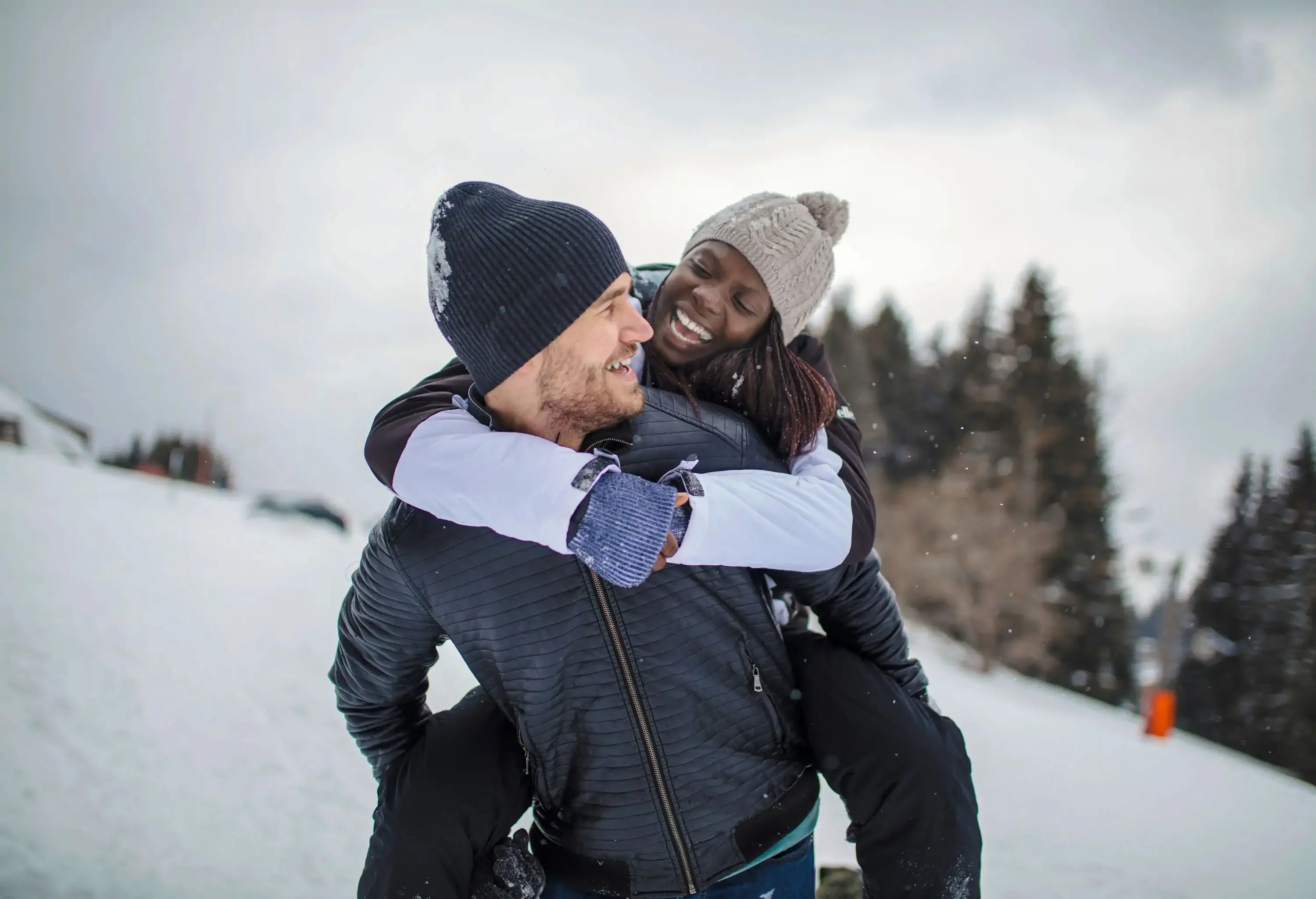 A couple enjoys a piggyback ride outdoors in winter.