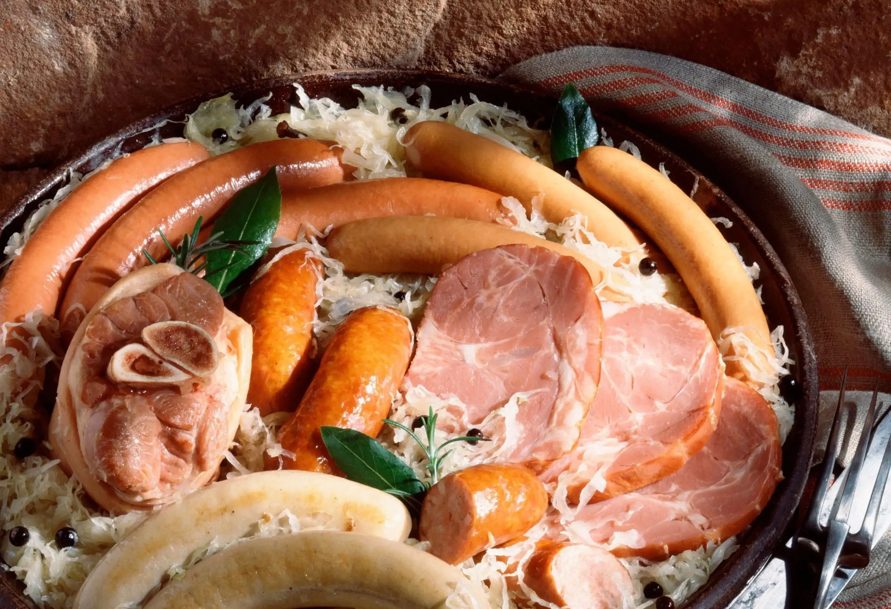 A dish with various types of meats and sausages served on a brown plate.