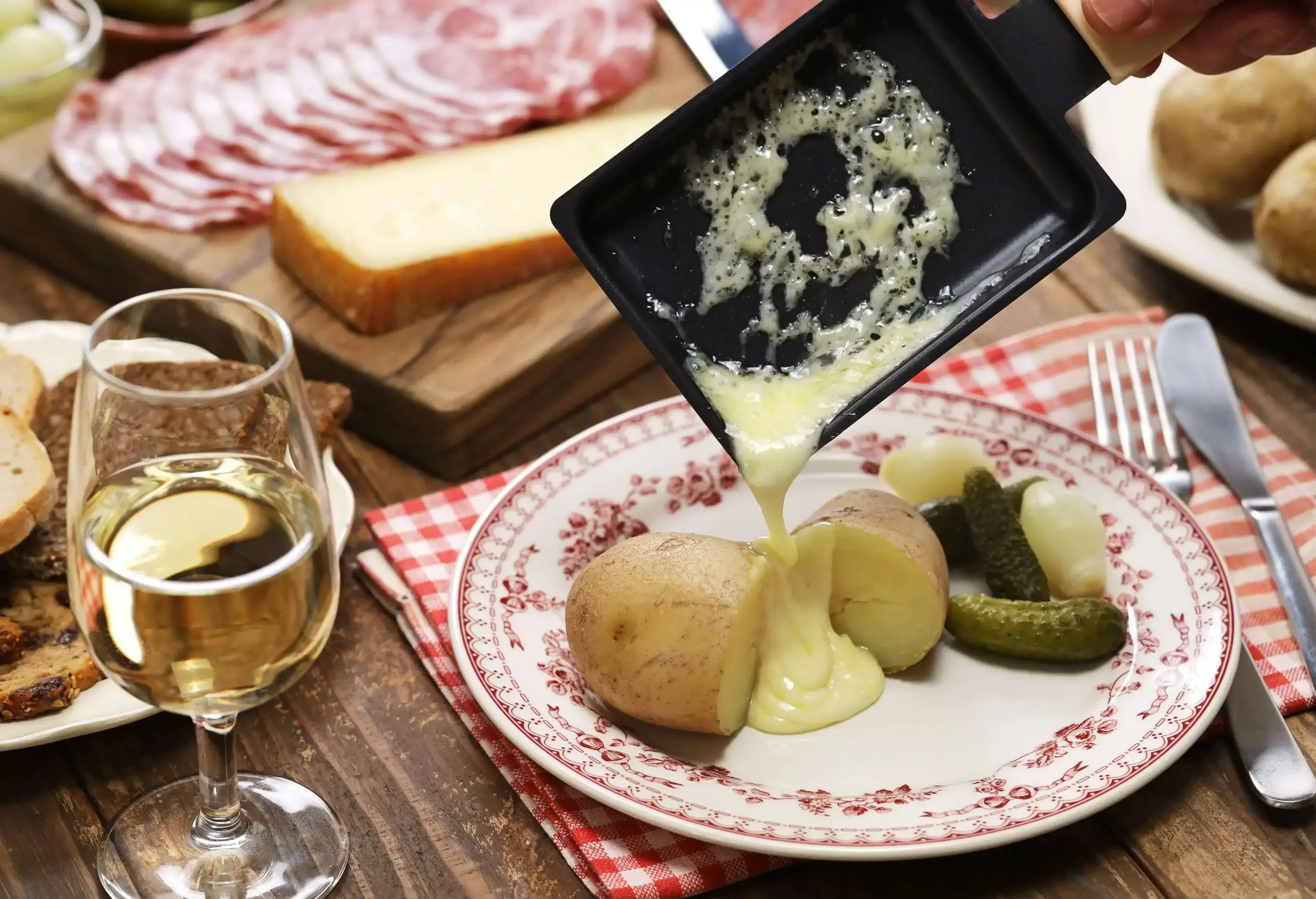 A pan of melted cheese poured into a plate of sliced potato.