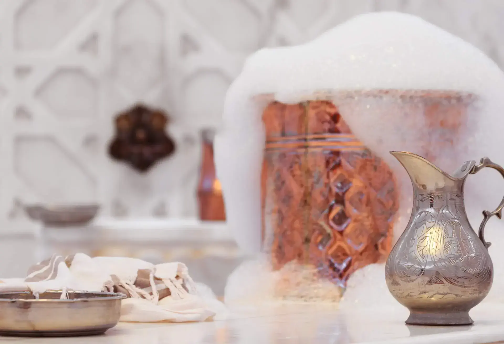 Water jar, towel and copper bowl with soap foam in turkish hamam. Traditional interior details. Horizontal, wide screen format