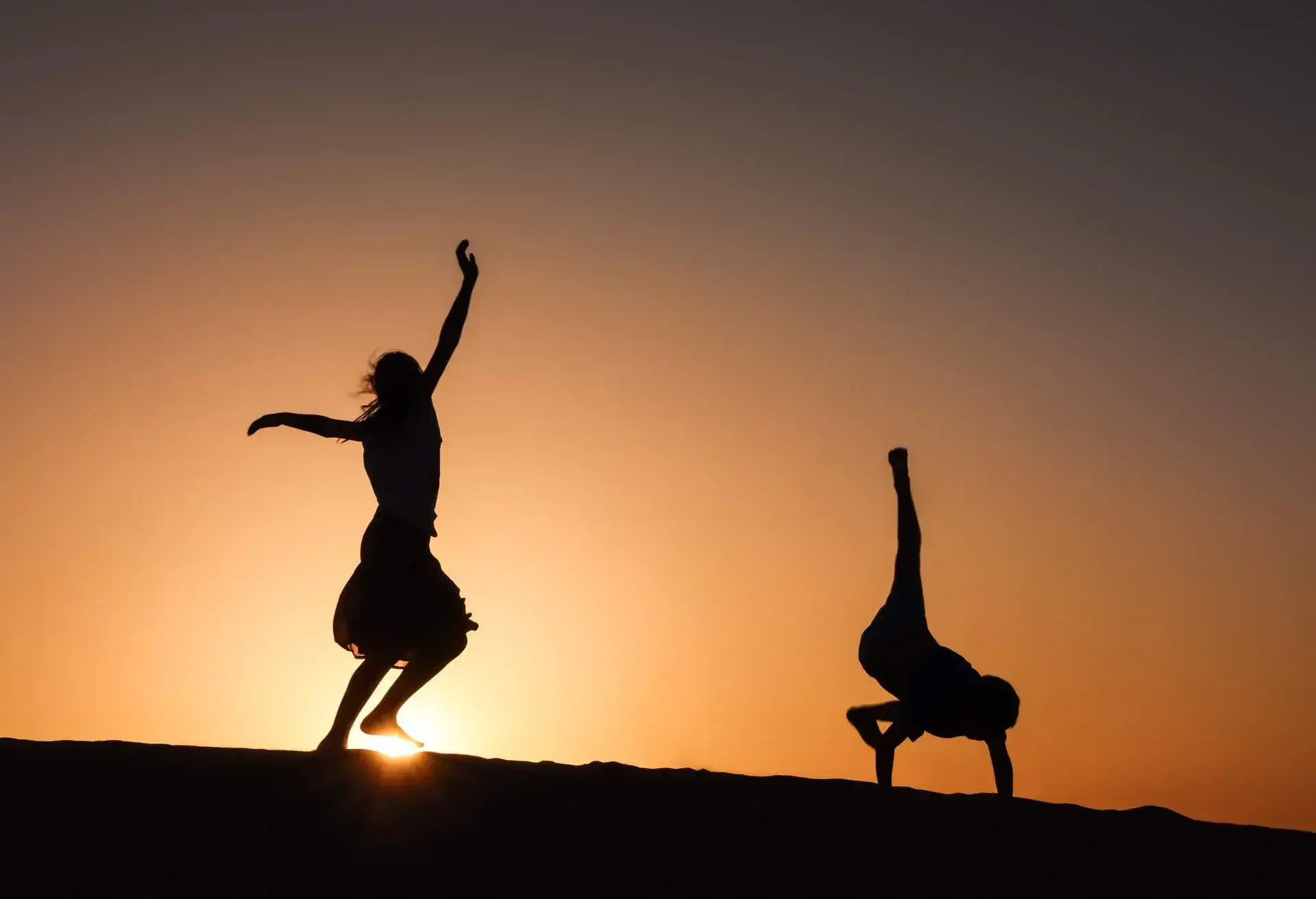 Sunset silhouette of 2 young child siblings in the desert
