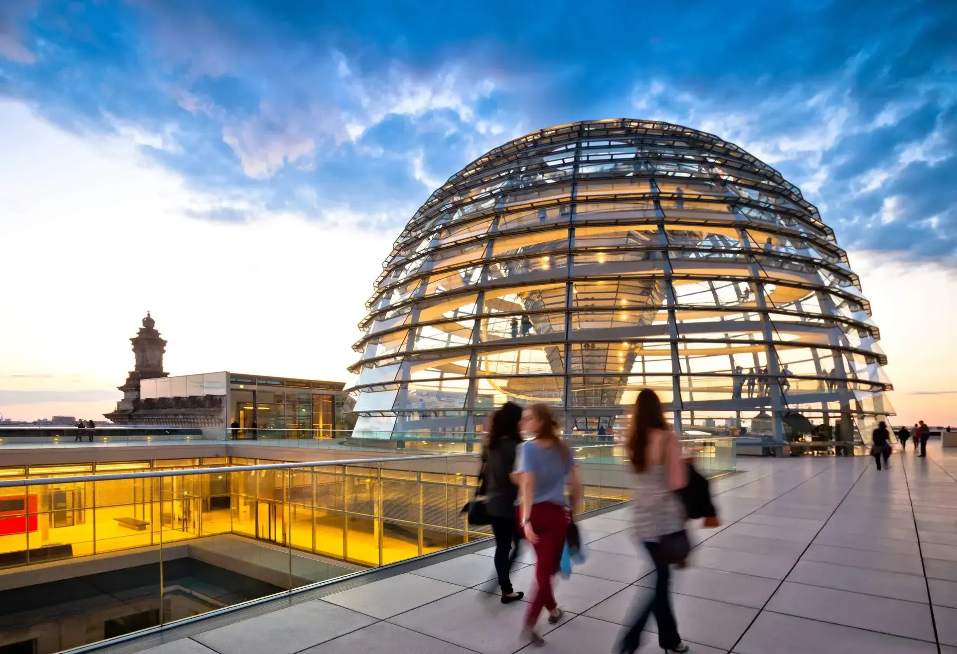 A group of people walk past a rooftop dome structure with glass façade.