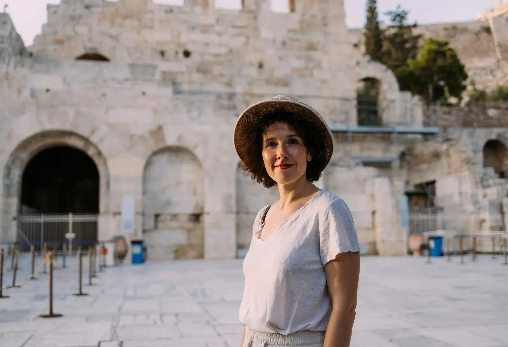 Happy young woman standing in front of the museum, smiling and looking at camera- traveling solo during COVID-19 Pandemics