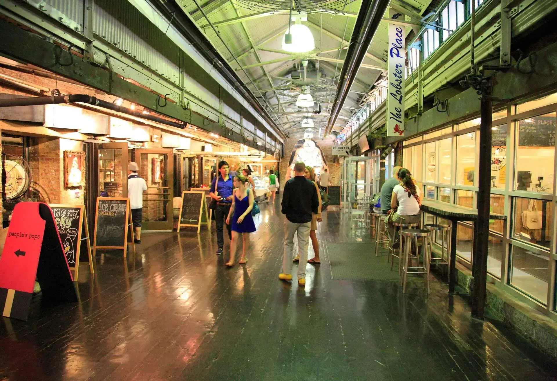 A market gallery with menu boards of restaurants and cafes along the side.