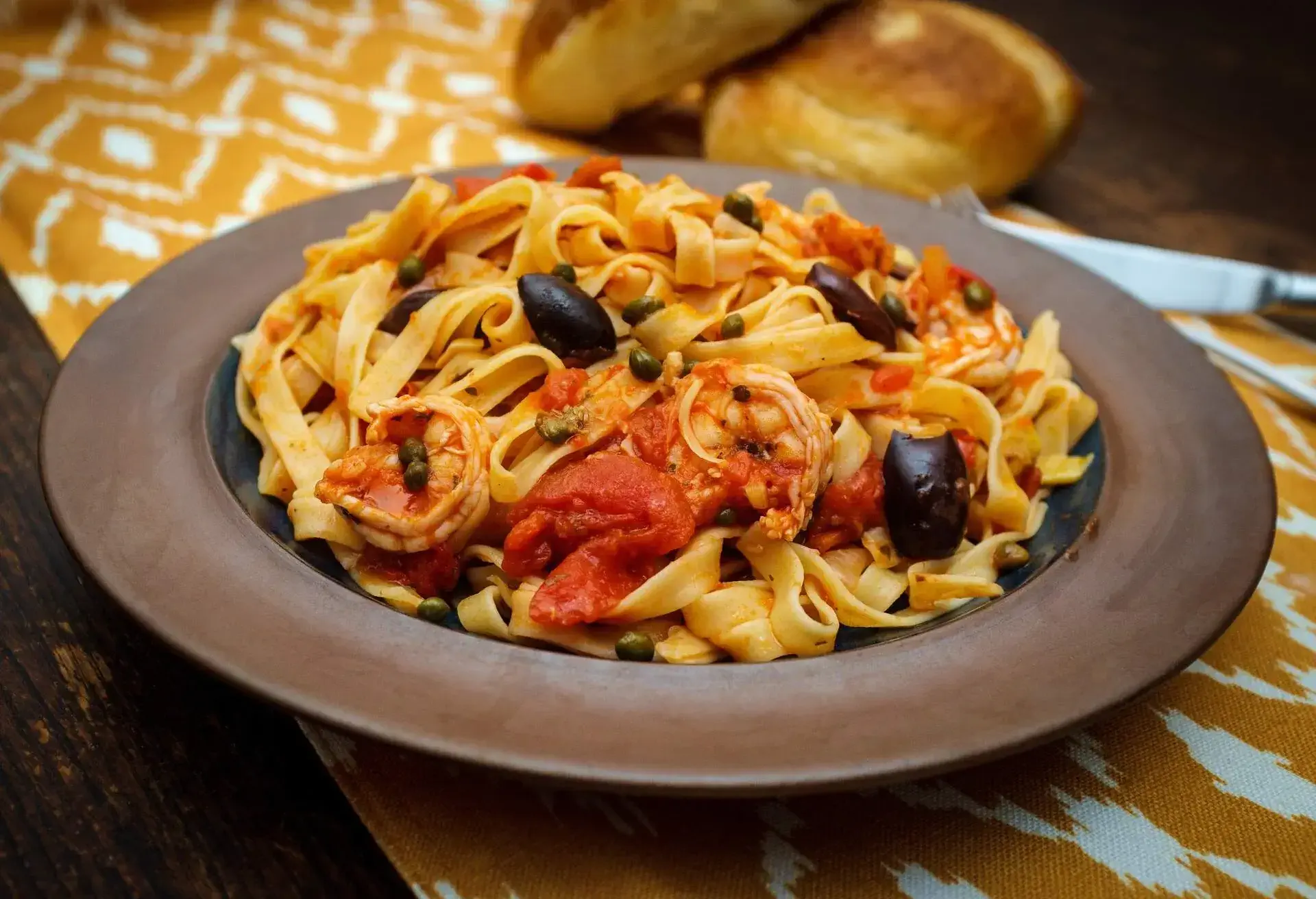 Delicious Spaghetti alla puttanesca with jumbo shrimp and fresh italian bread