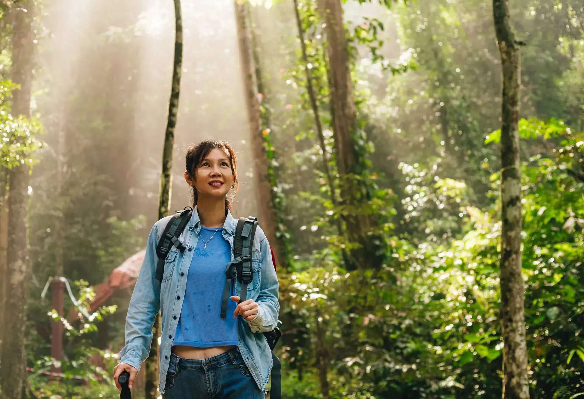 Woman with backpack exploring nature outdoor in tropical rainforest and enjoying nature.