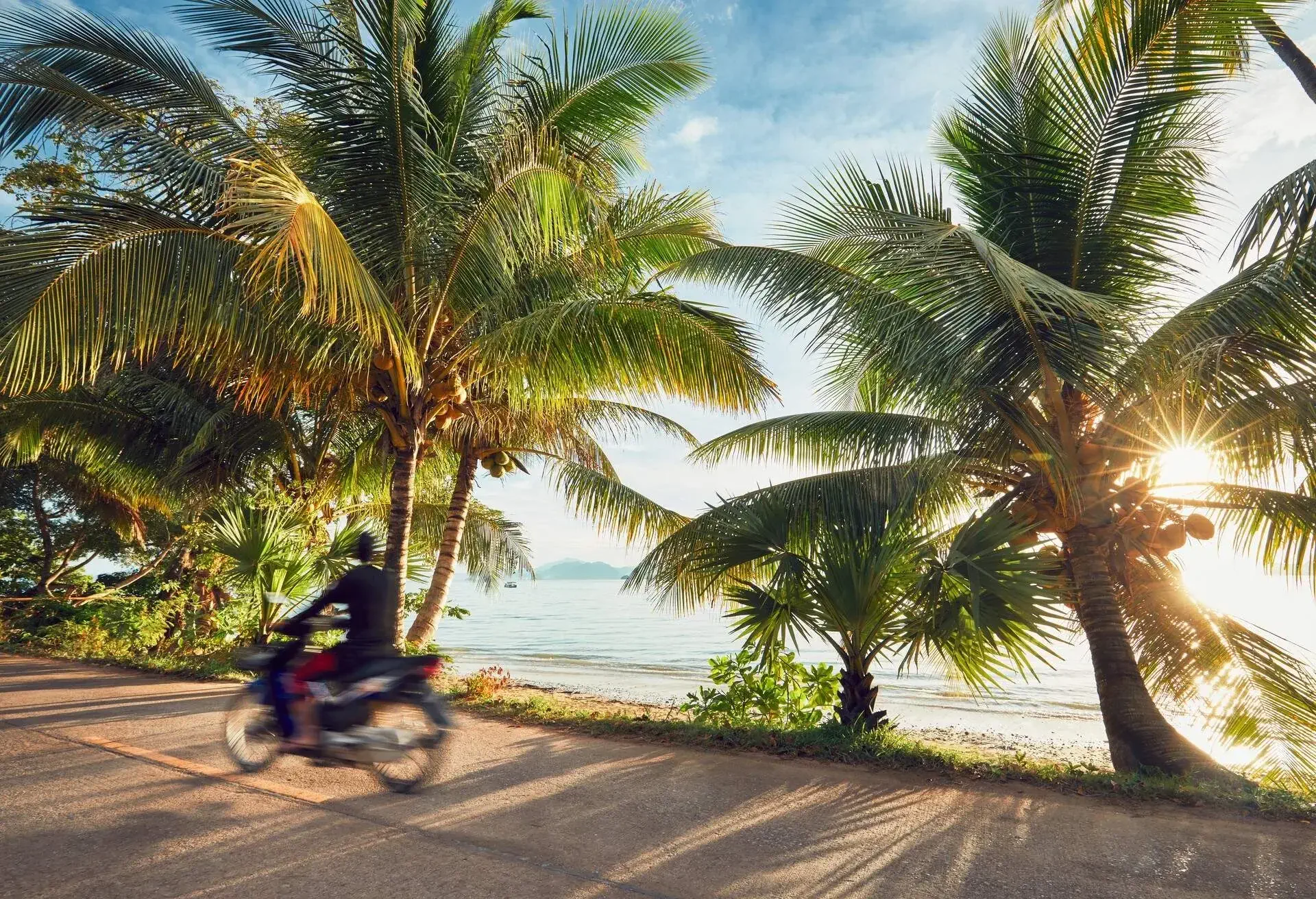 Tourist is driving motorbike on the tropical island at the sunrise. Koh Yao Noi, Thailand
