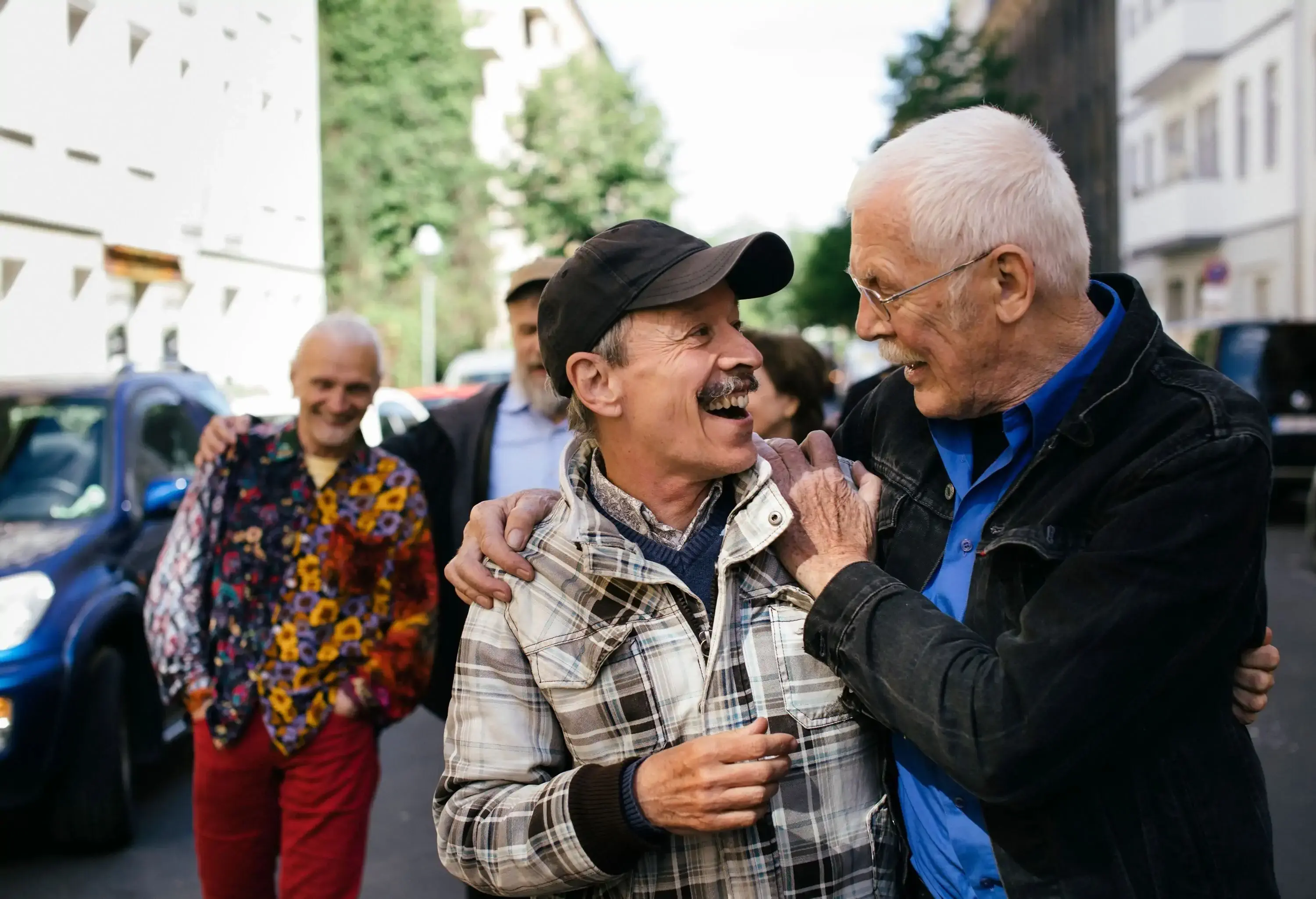 A group of happy and elderly gay people embrace as they walk on the street.