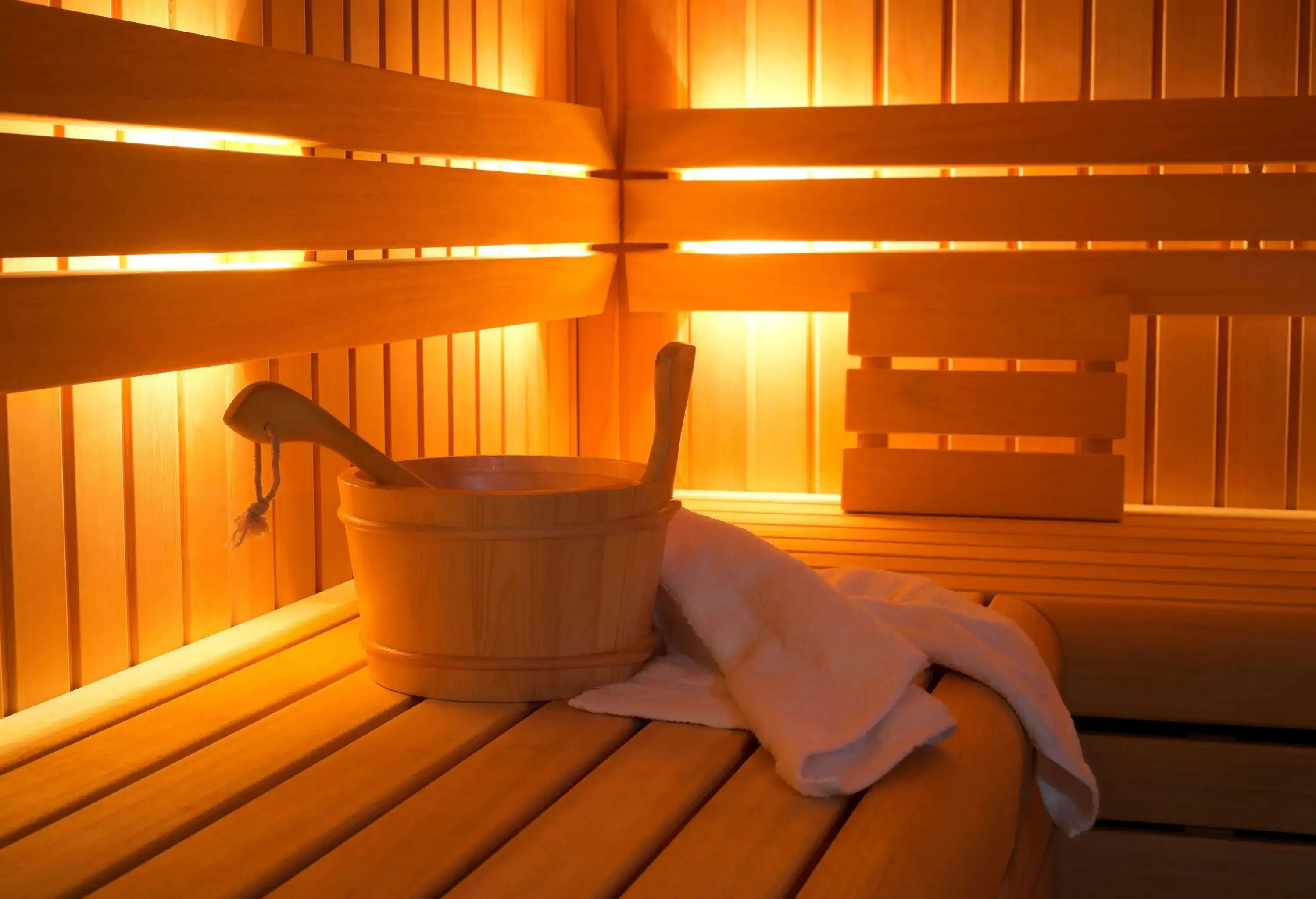 A wooden bucket and a towel inside a sauna.
