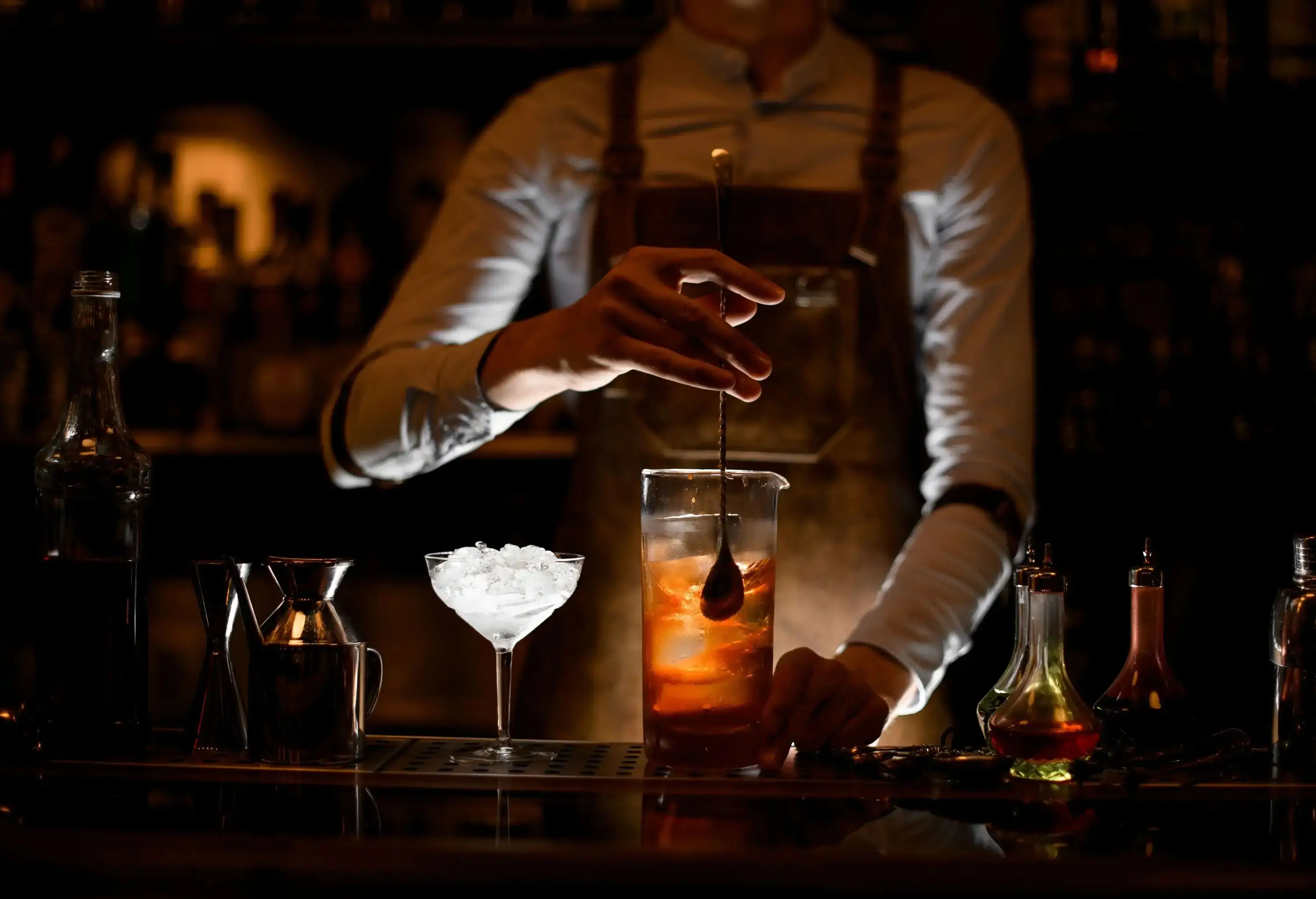 A bartender mixing drinks behind a counter.