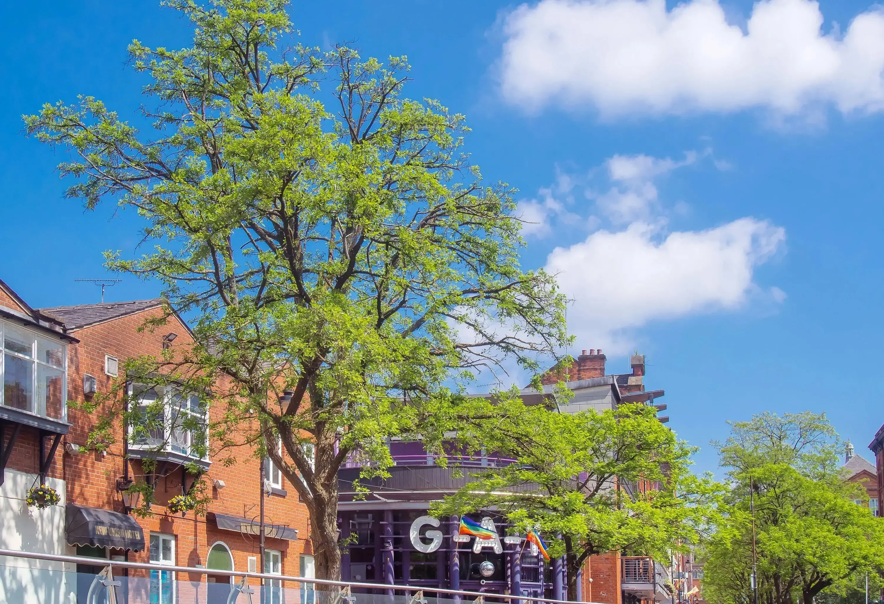 A gay bar in the centre of traditional brick buildings against the cloudy blue sky.