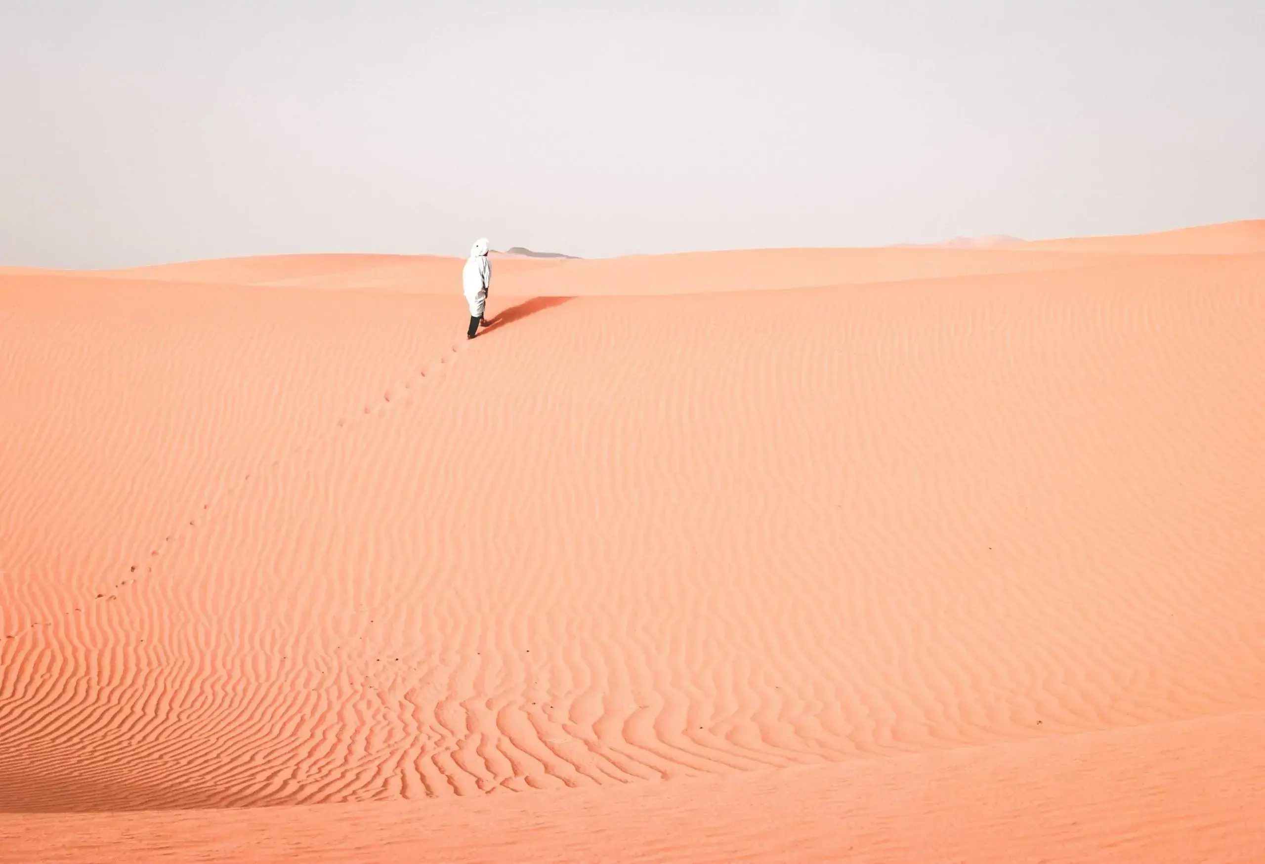 An individual in a traditional white dress on a desert.