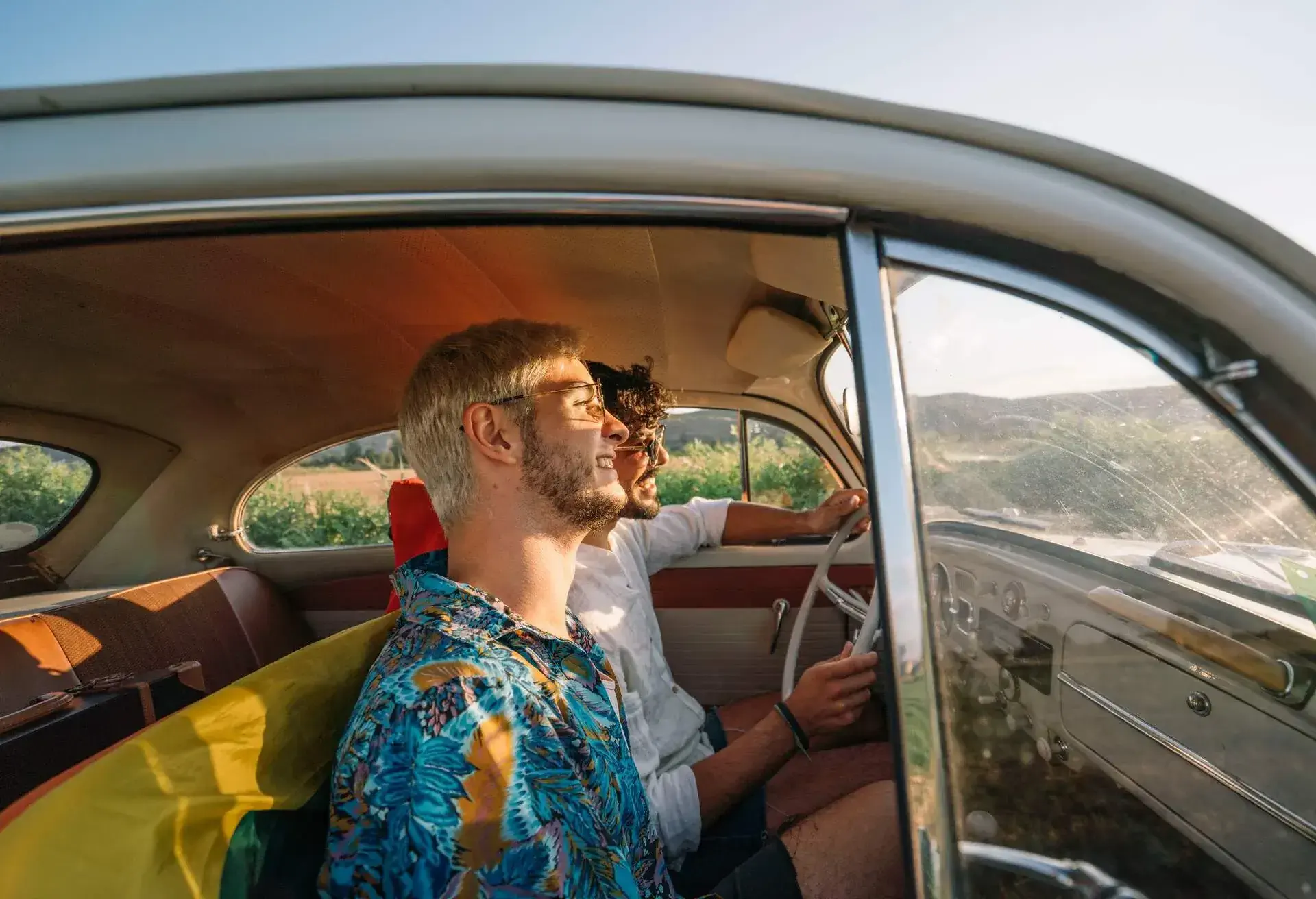 Two friends riding in the front seats of a vintage car.