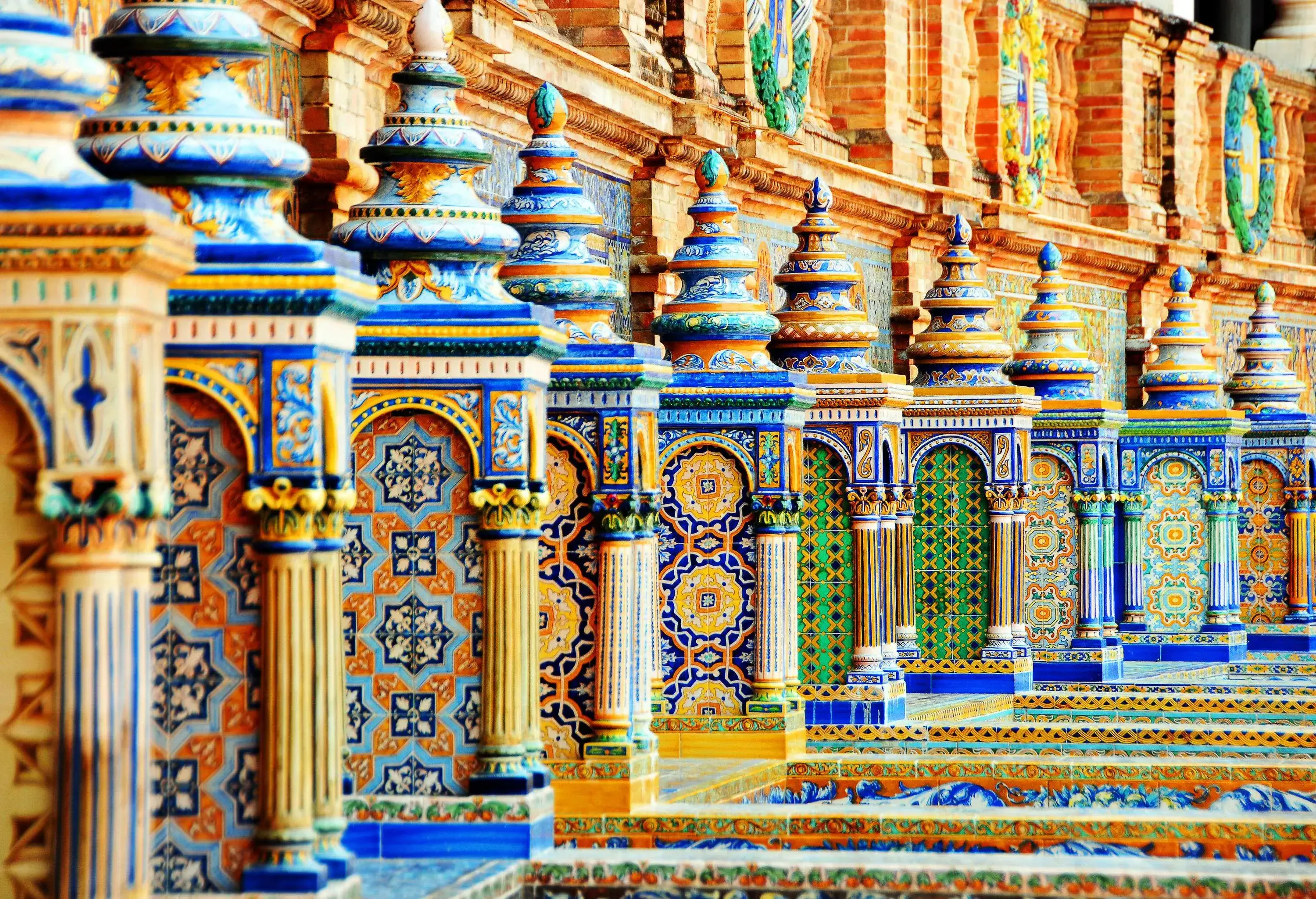 A row of small pillars adorned with colourful ceramic tiles with unique patterns on the alcoves.