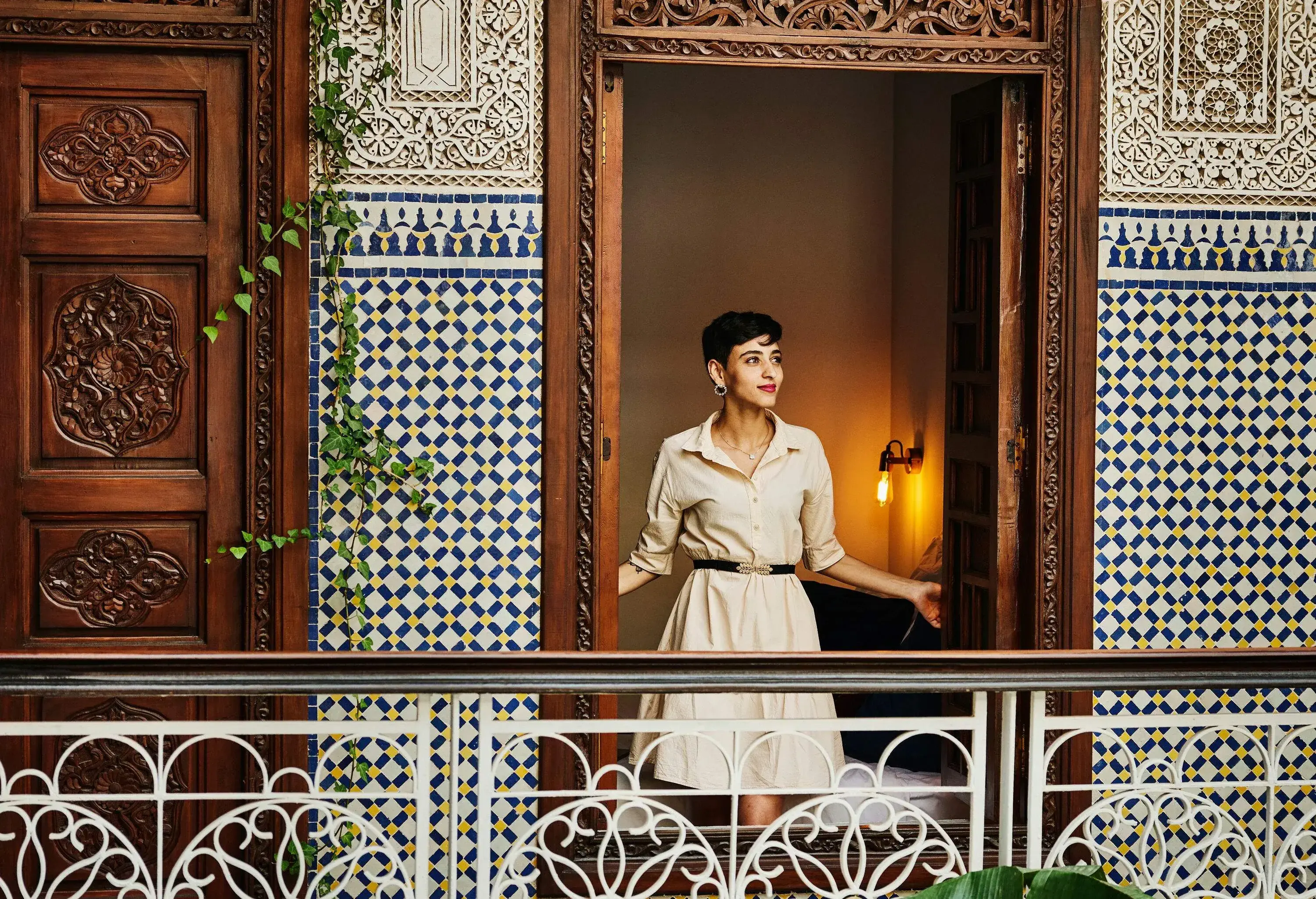 Wide shot portrait of smiling woman standing in window of bedroom in riad while on vacation in Marrakech
