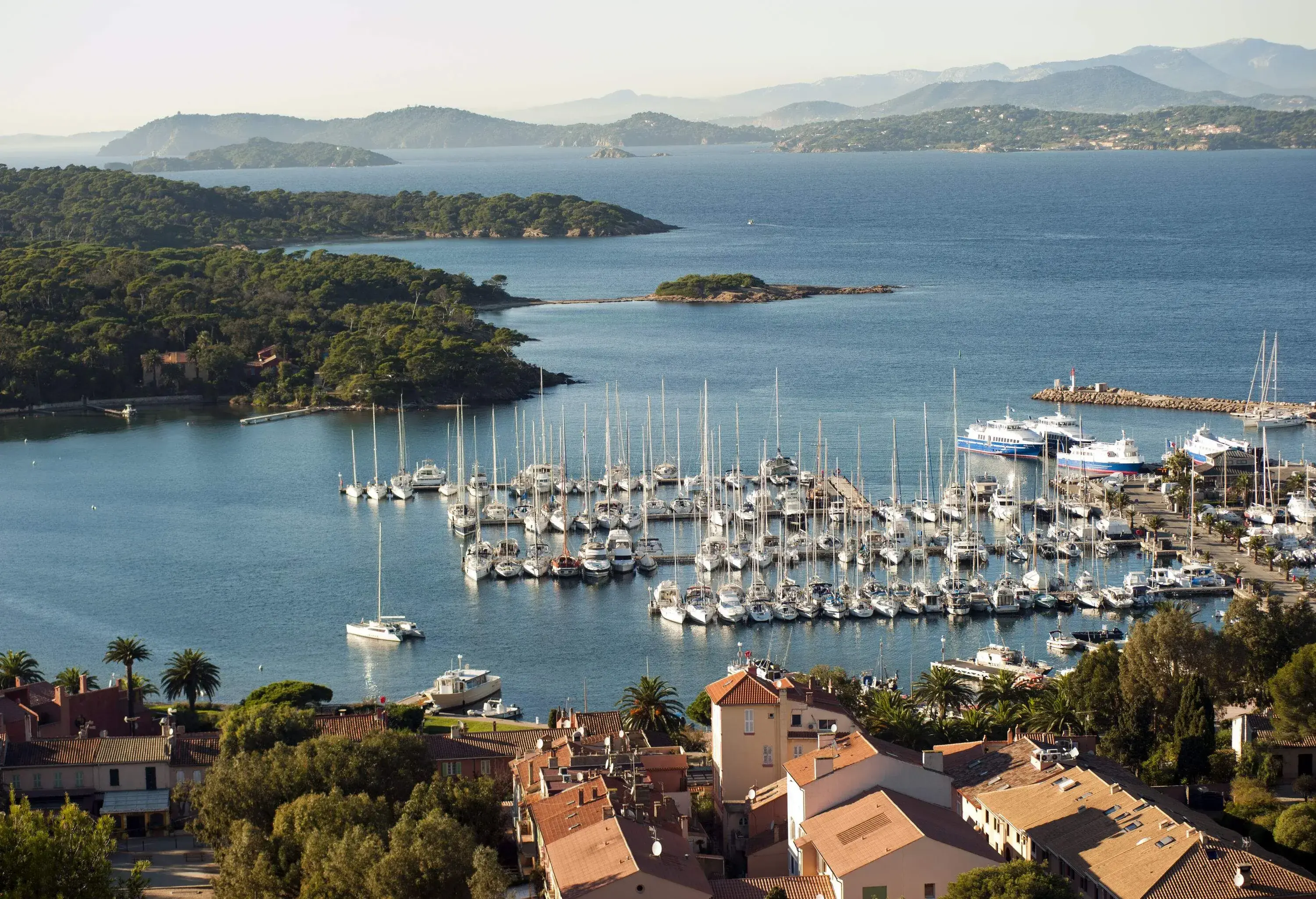 White boats moored on the port of a lush coastal seaside city.