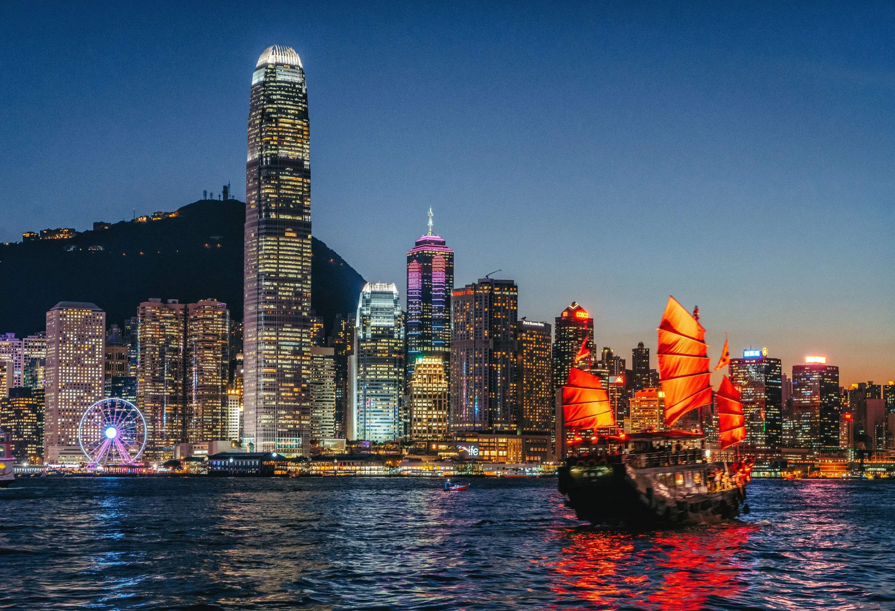 Skyline of a brightly lit modern city with towering buildings at twilight.