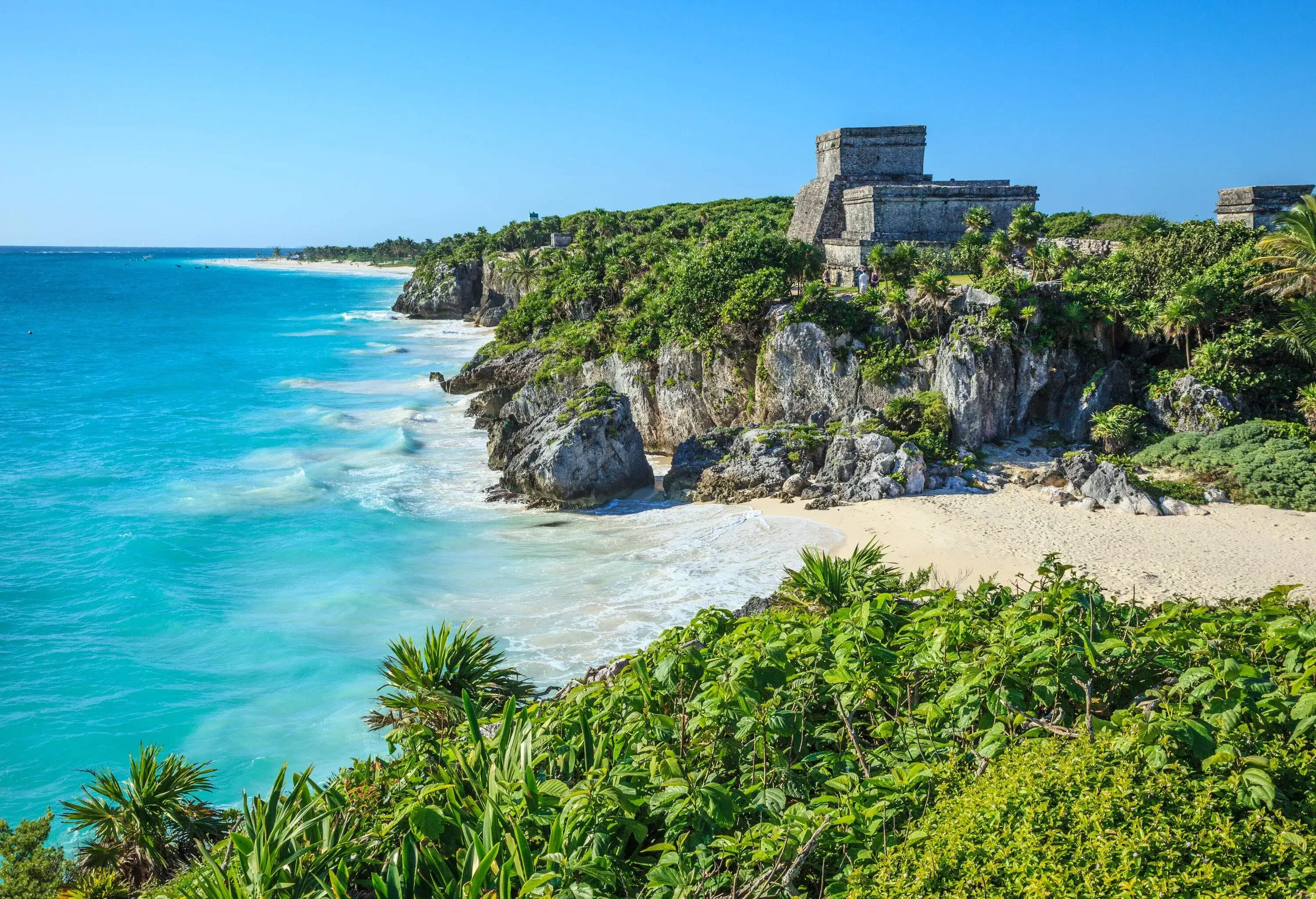 The Tulum Mayan ruins perched on a forested clifftop overlooking the turquoise ocean.