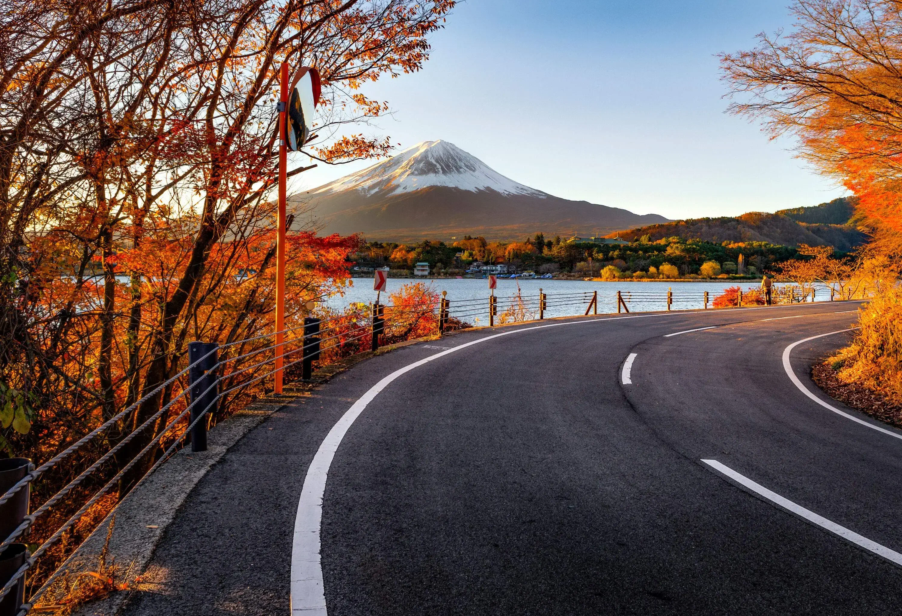 A view of Mount Fuji from a road without traffic with autumn foliage on a crisp sunny day