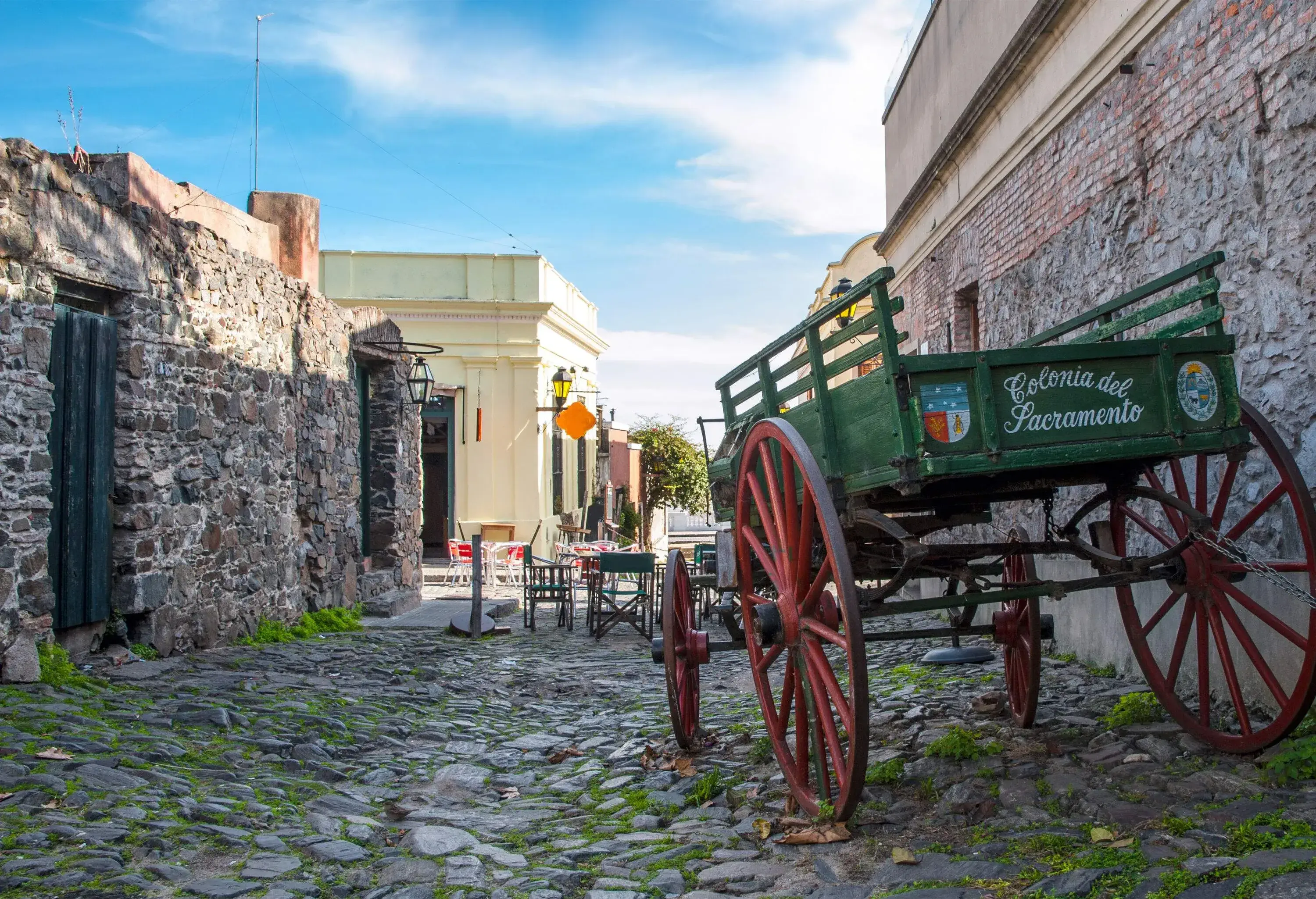 A cobblestone street in a neighbourhood with a parked carriage.