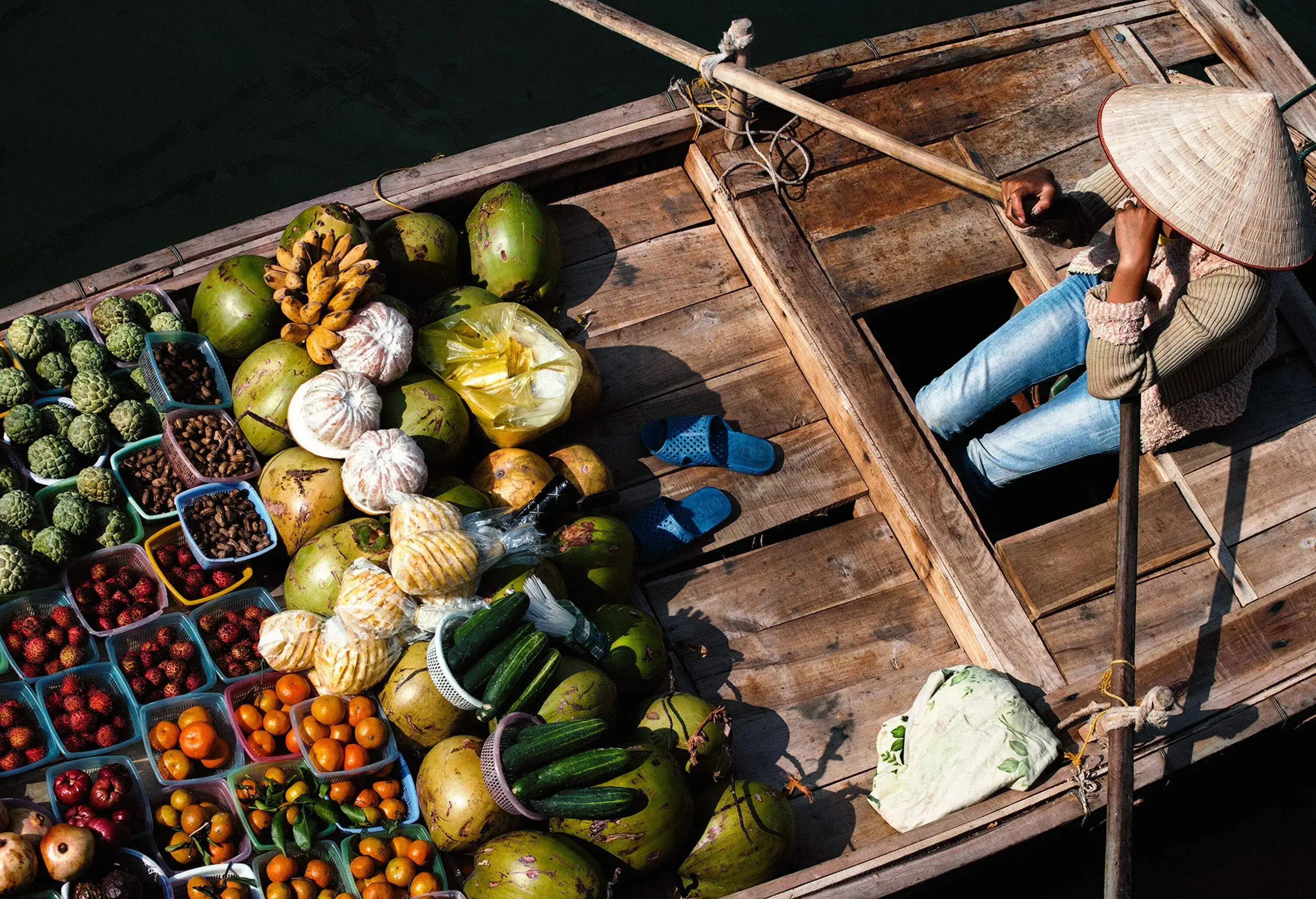 A lady fruit vendor sits on her wooden boat.