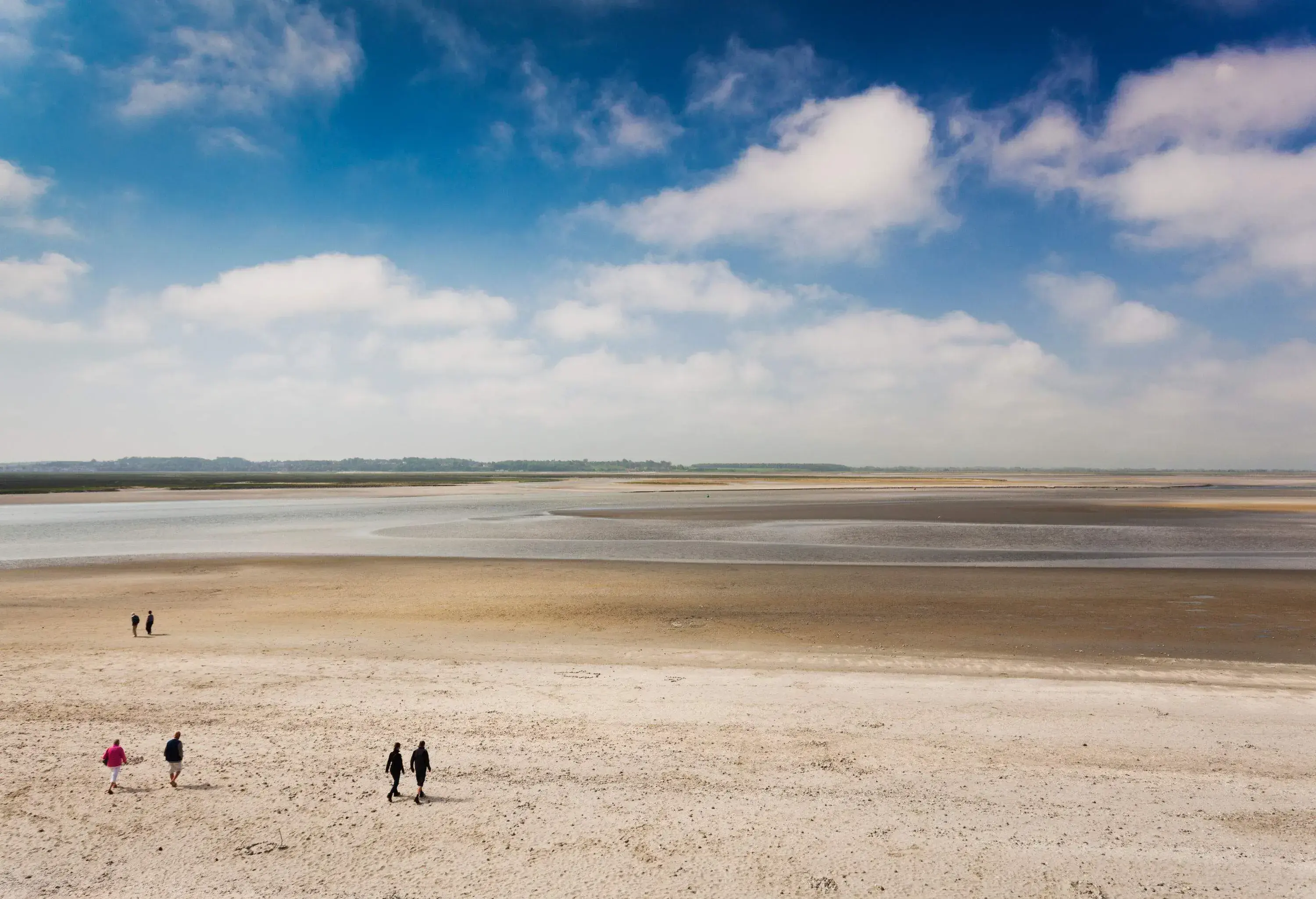 People walking across the beach at low tide.
