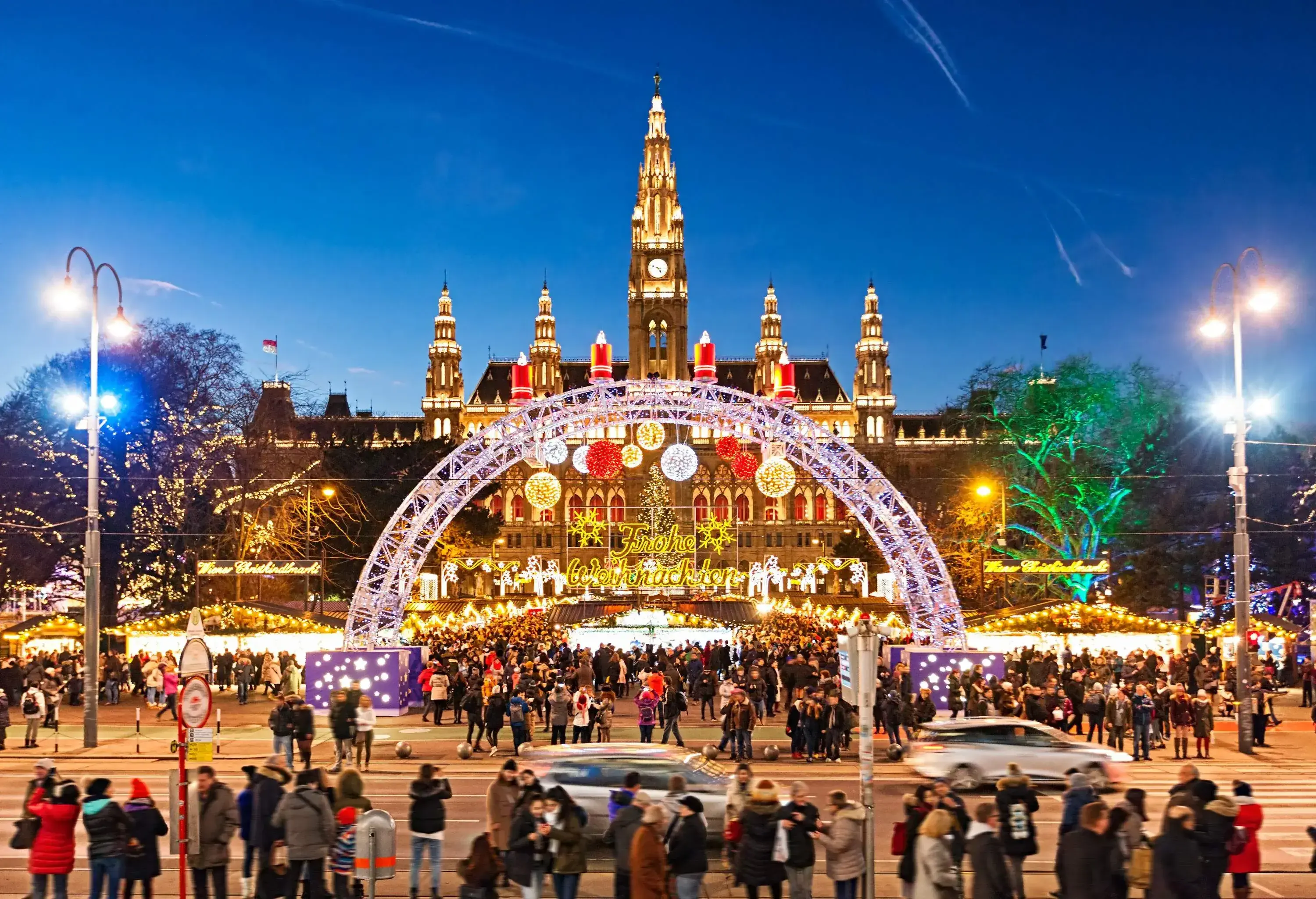 A spectacular Christmas market entrance arch set against the stunning grandeur of an illuminated old town hall.