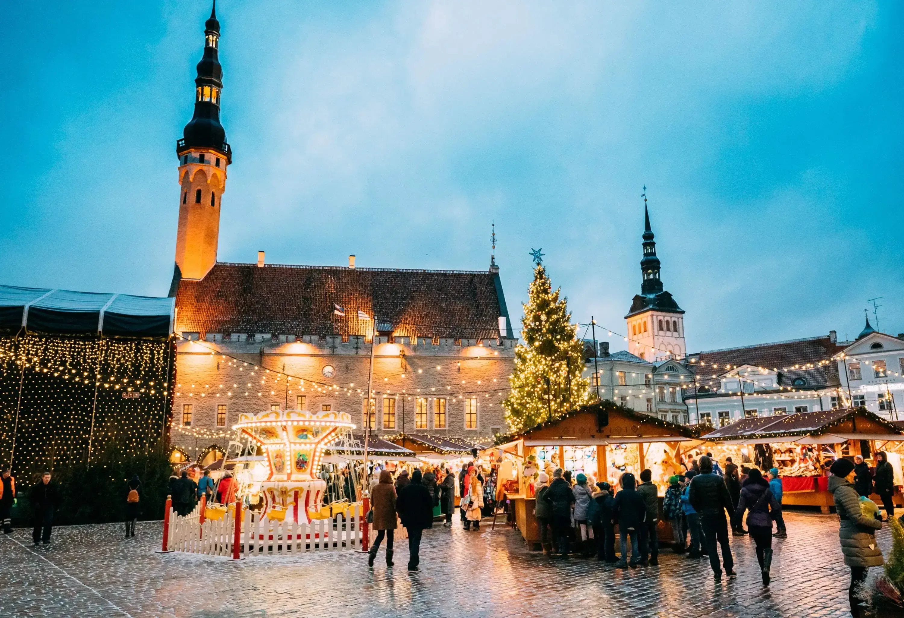 A beautiful Christmas fair with a golden glow in the middle of a plaza complete with a Christmas tree, a small carousel, and shops.