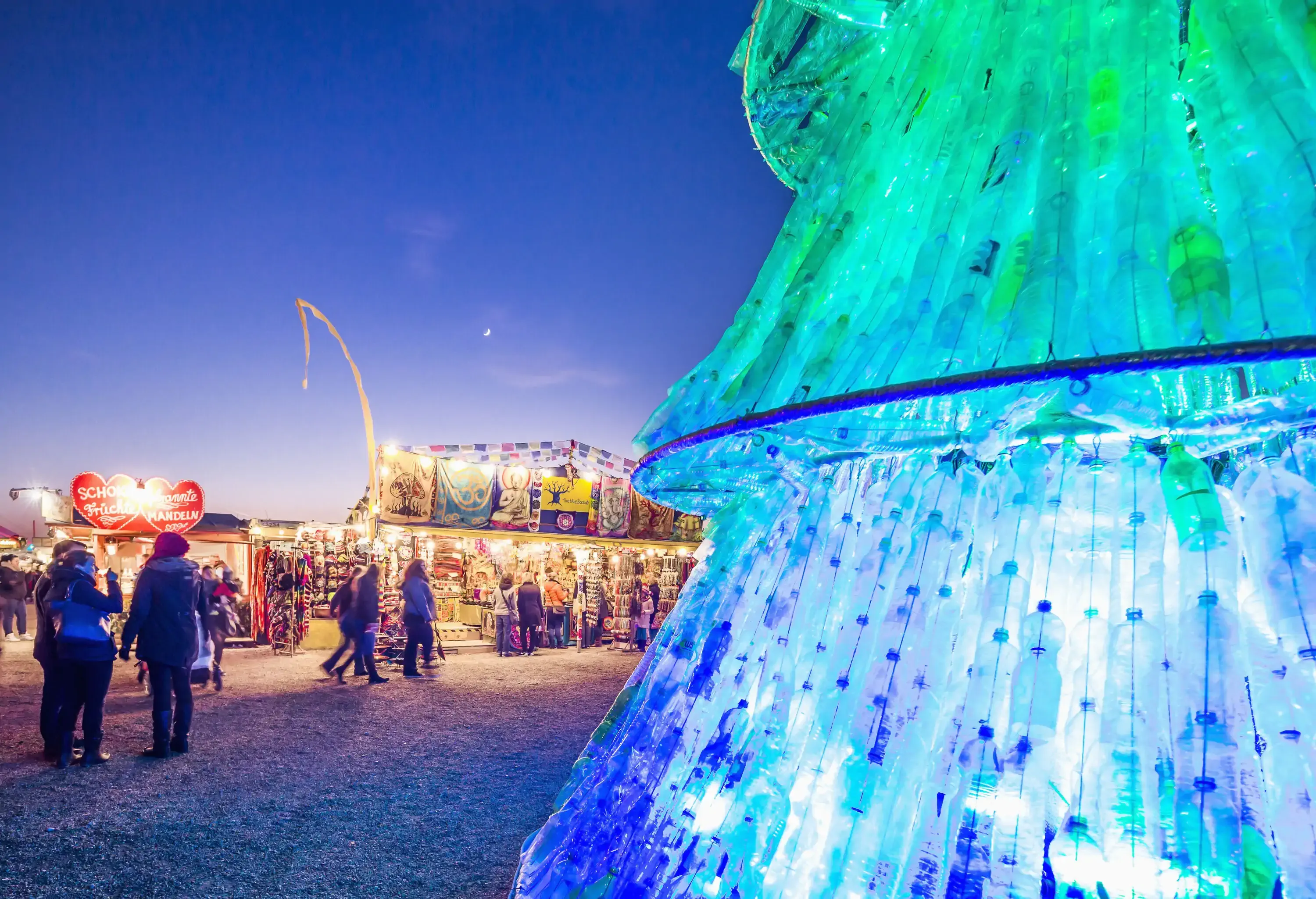 A Christmas tree made from discarded bottles strung together and surrounded by seasonal stores.