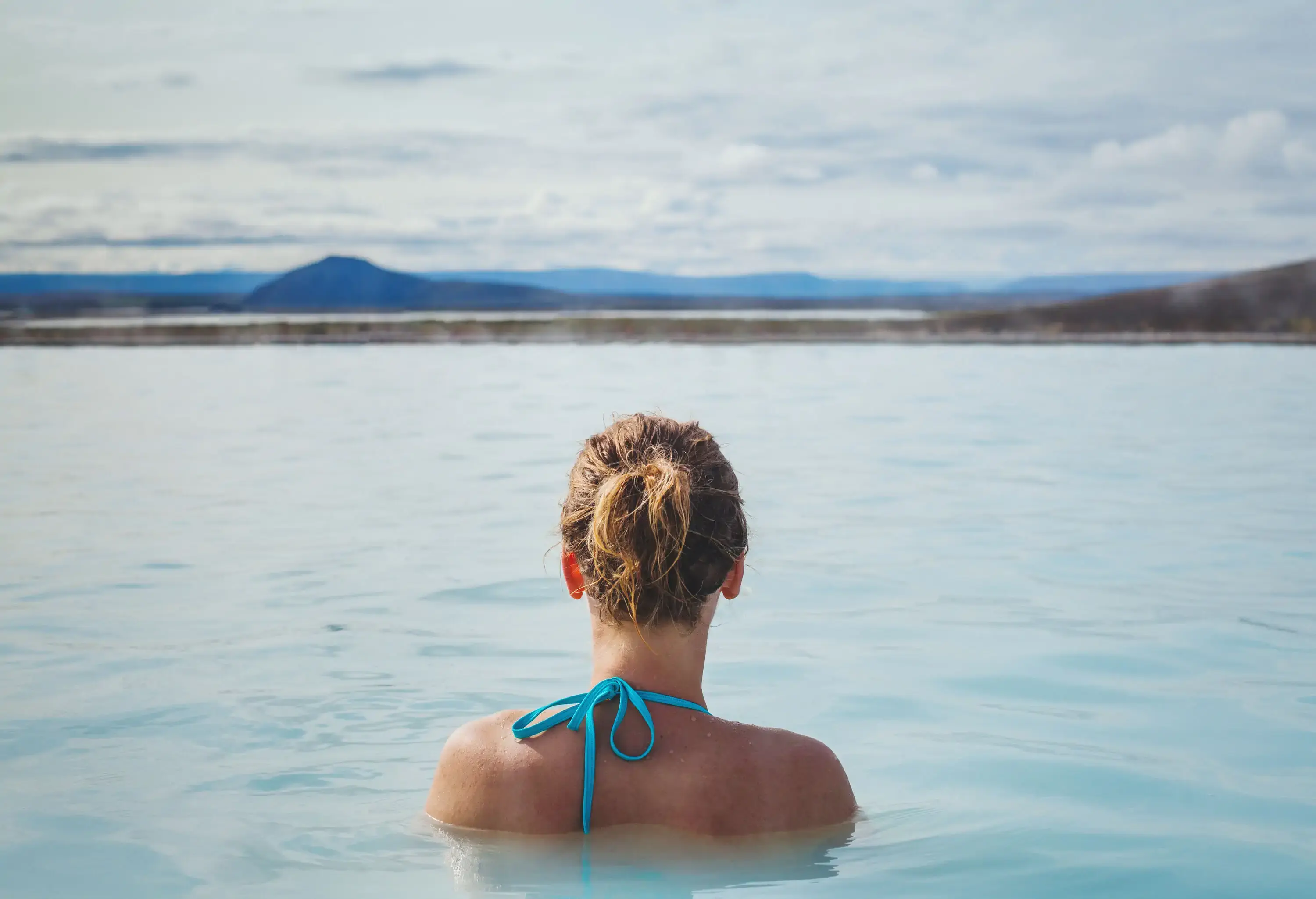 A woman bathing in the milky water of the Blue Lagoon.