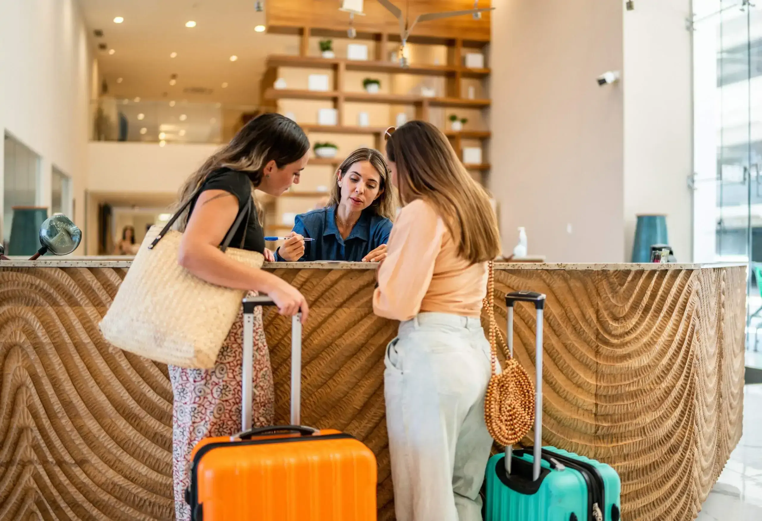 theme_travel_hotel_front_desk_lobby_people_receptionist_guests_women_gettyimages-1484358444