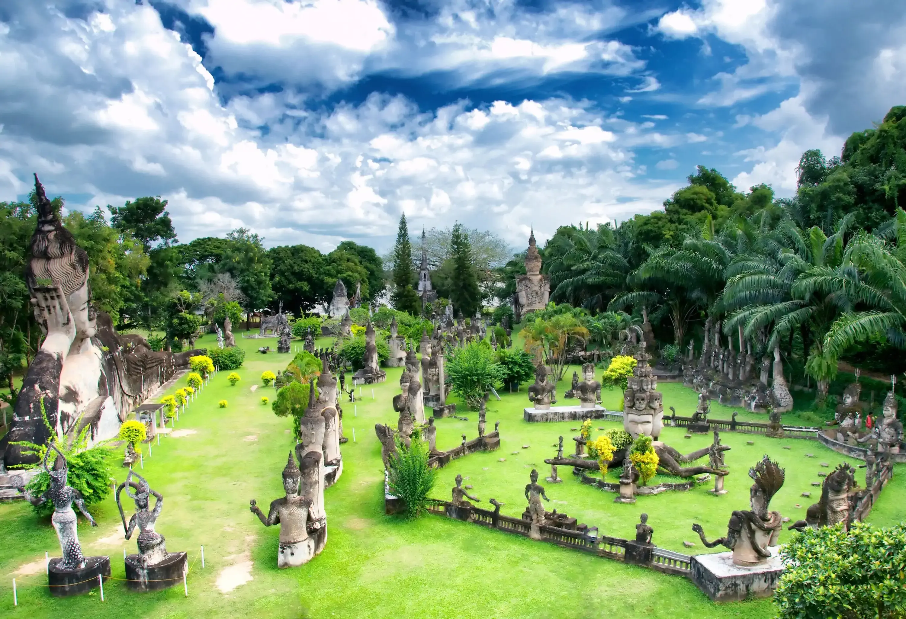 An outdoor sculpture garden containing numerous Hindu and Buddhist statues concealed within the lush green trees.