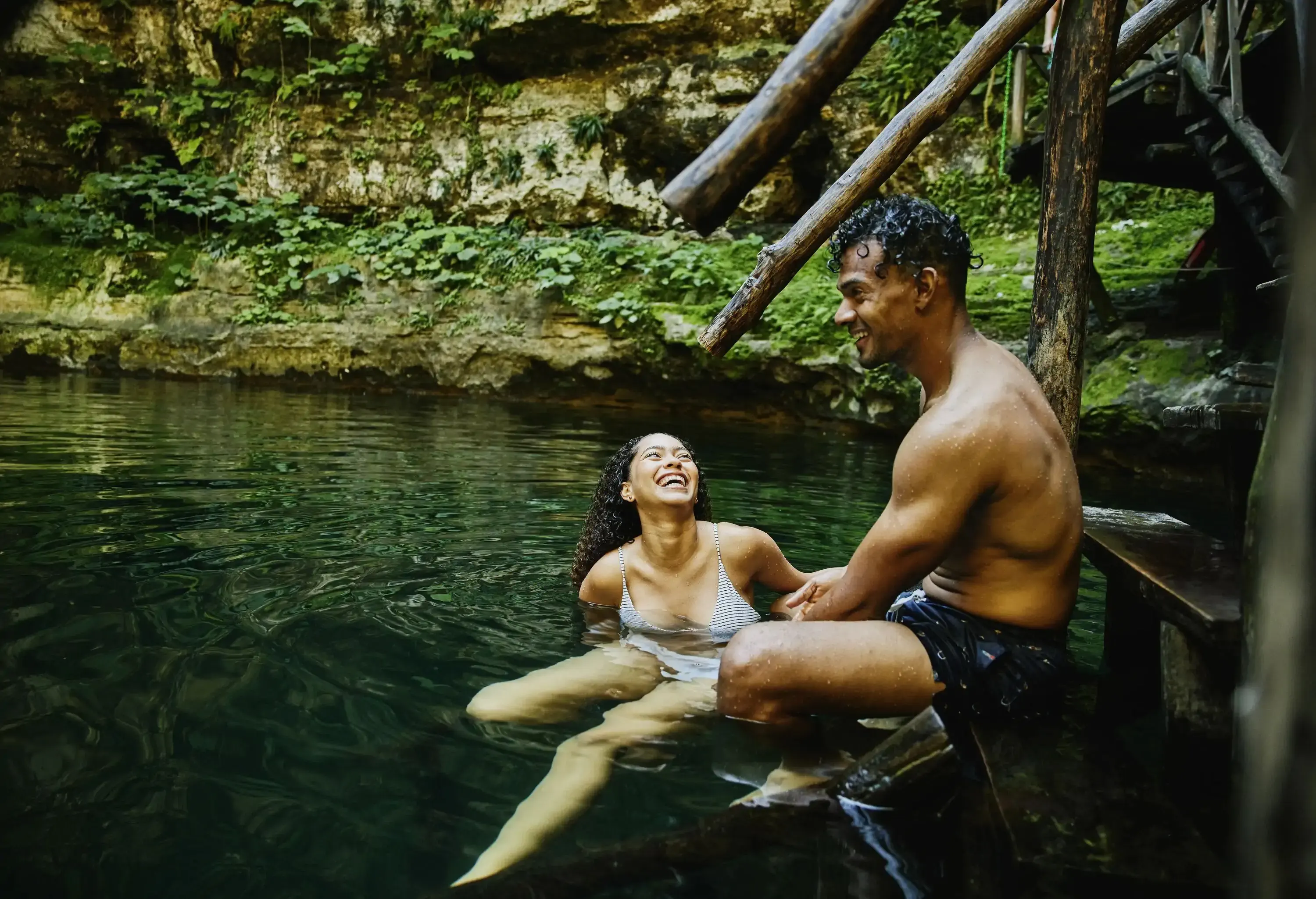 Couple sat by stairs in a cenote laughing