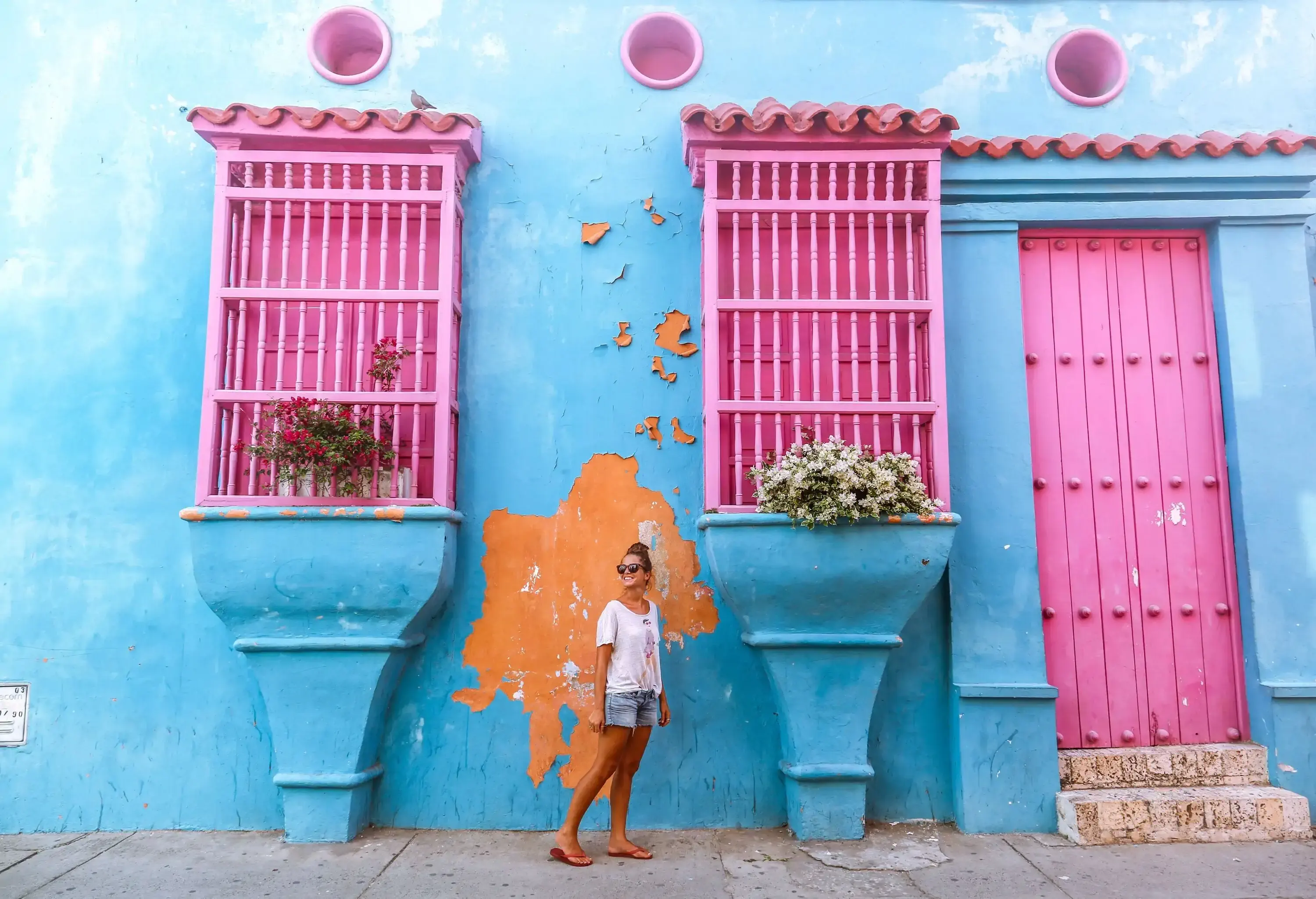 Female traveller standing by colourful walls of a colonial building in tropical country