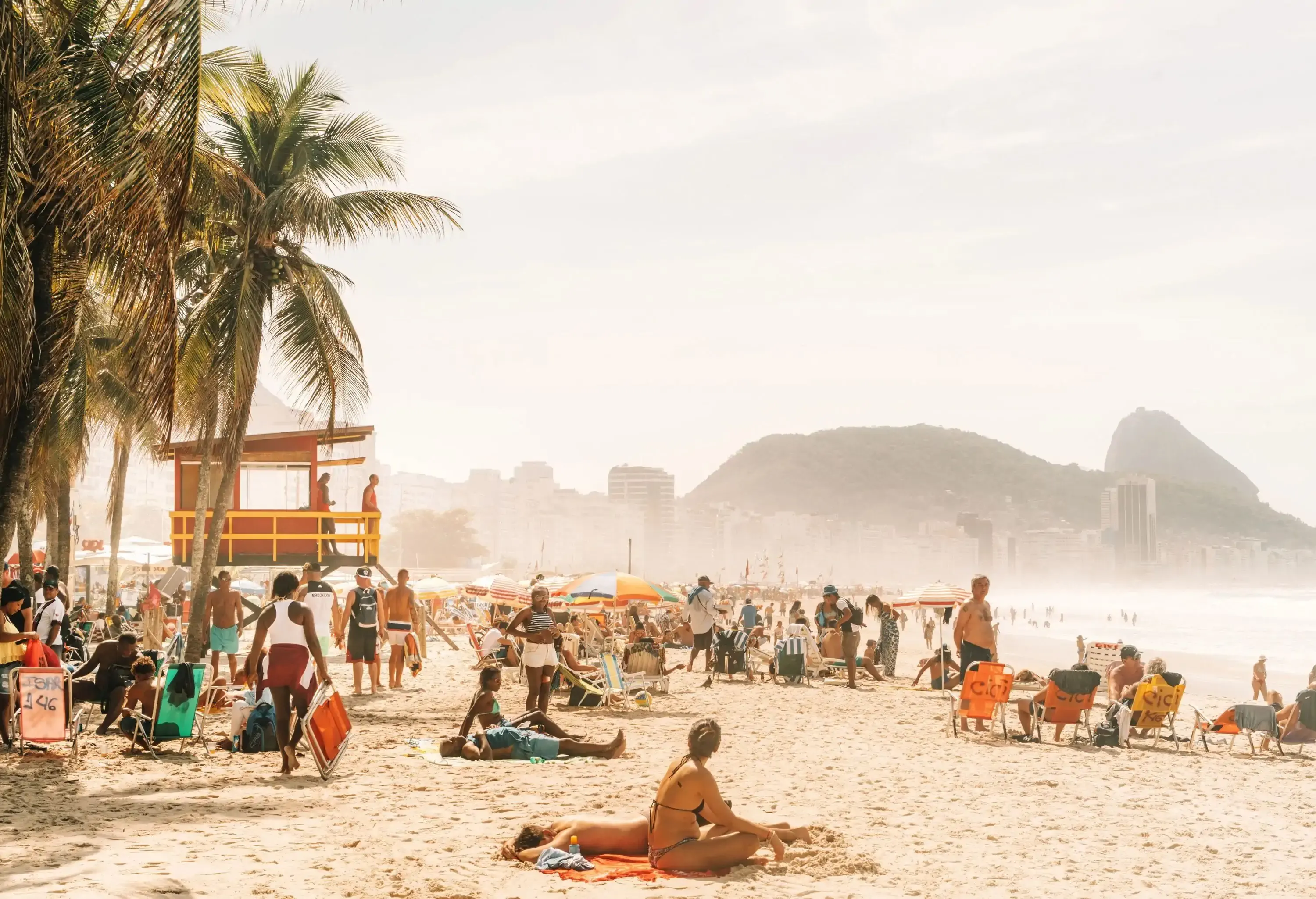 people relaxing and sunbathing at famous Copacabana beach on a hazy day