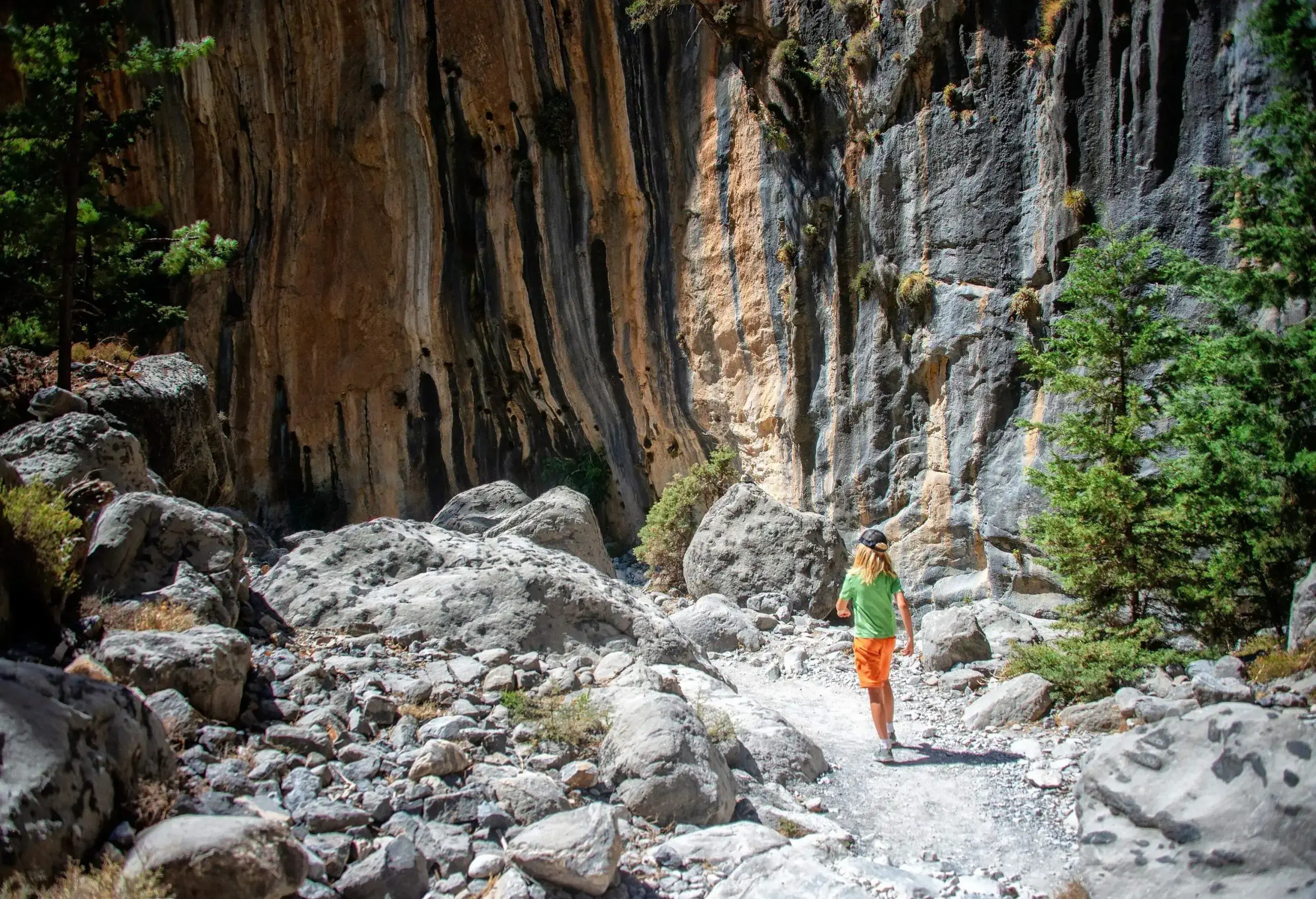 A young child strolling down a rocky path towards the gorge's colourful walls.