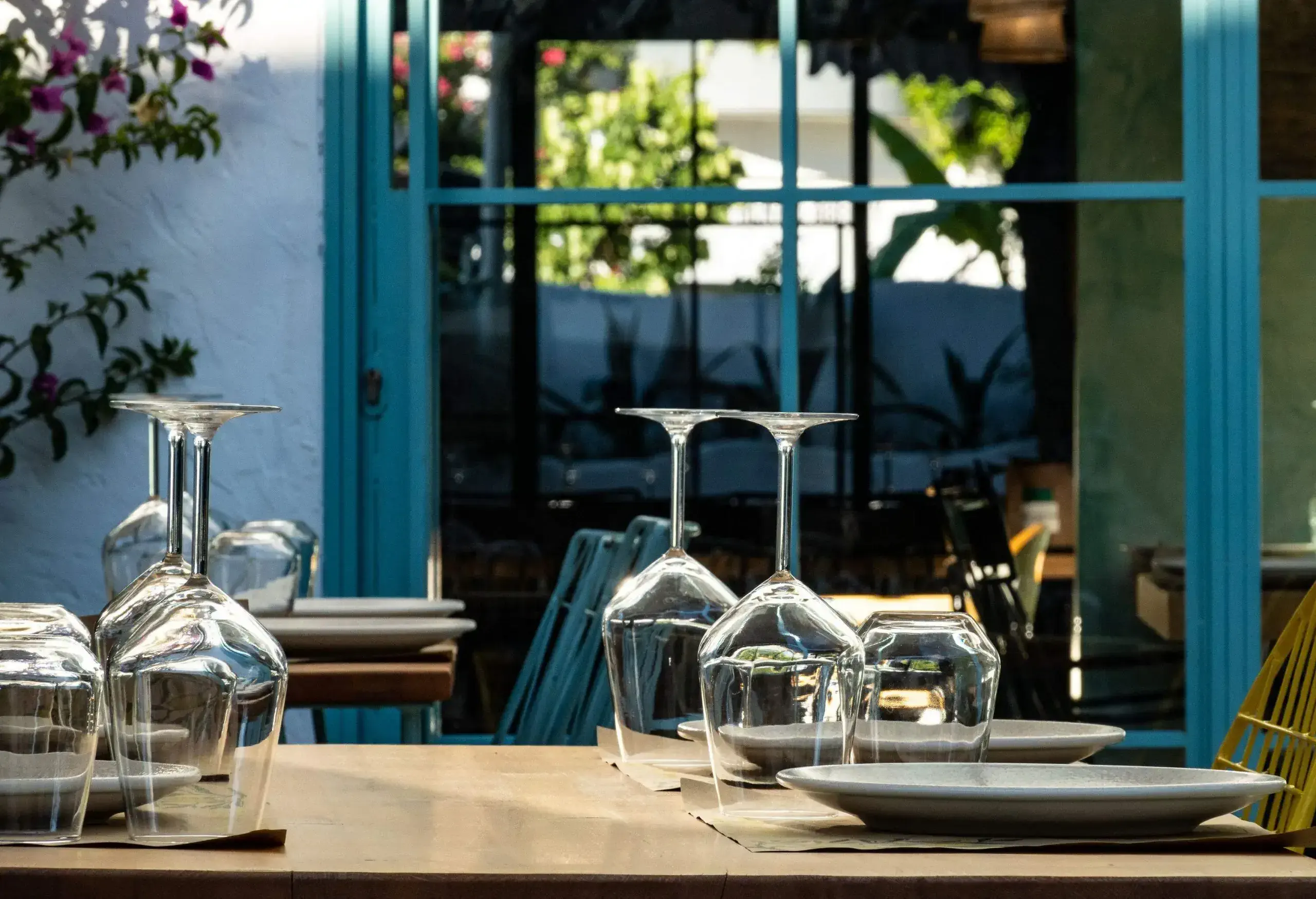 An inviting al fresco table setting features upside-down wine glasses set alongside plates.