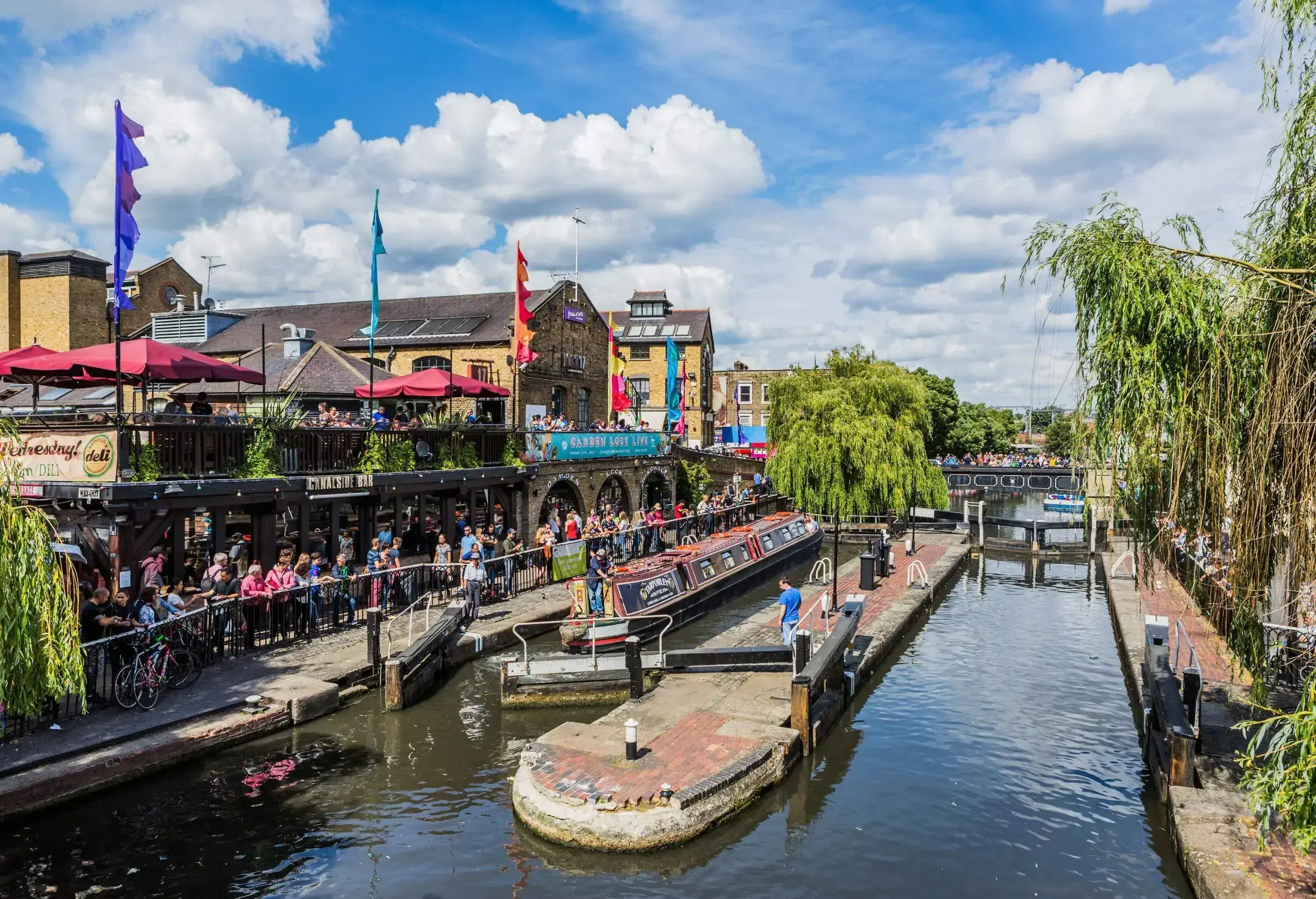 People along the side of the canal watching a boat passing through the famous Camden Lock.