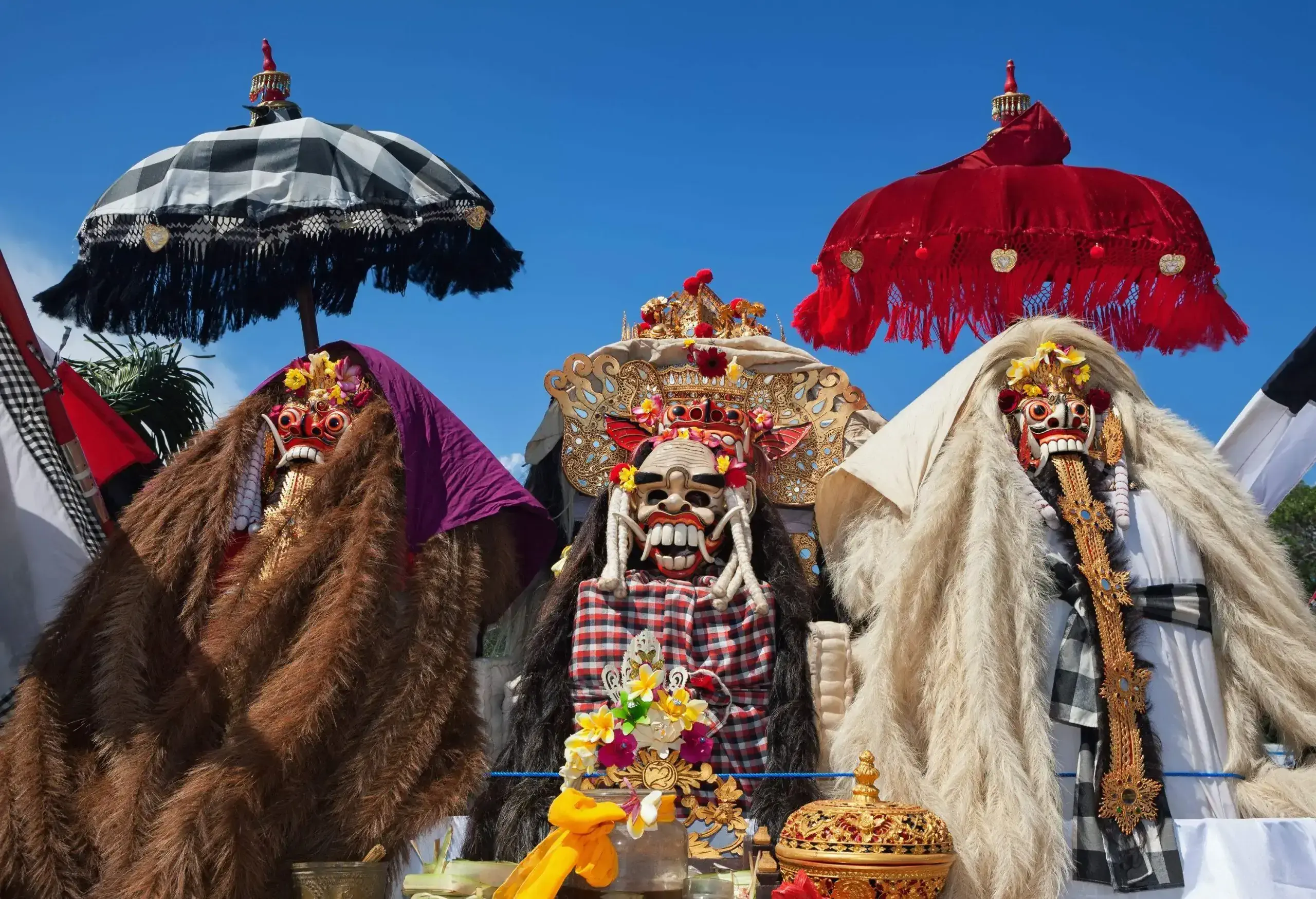 Traditional Rangda and Barong masks, which resemble masked figures of good and bad creatures, dressed in fur cloaks with vibrant umbrellas.