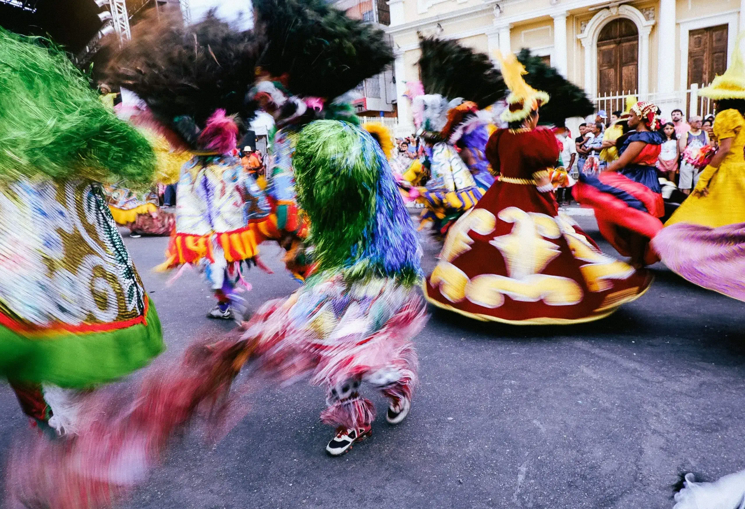 A dazzling display of colourful costumes and spirited dancing fills the streets during the traditional Maracatu Rural performance at the Carnival of Pernambuco, as enthralled spectators line the sidewalks to revel in the region's rich cultural heritage.