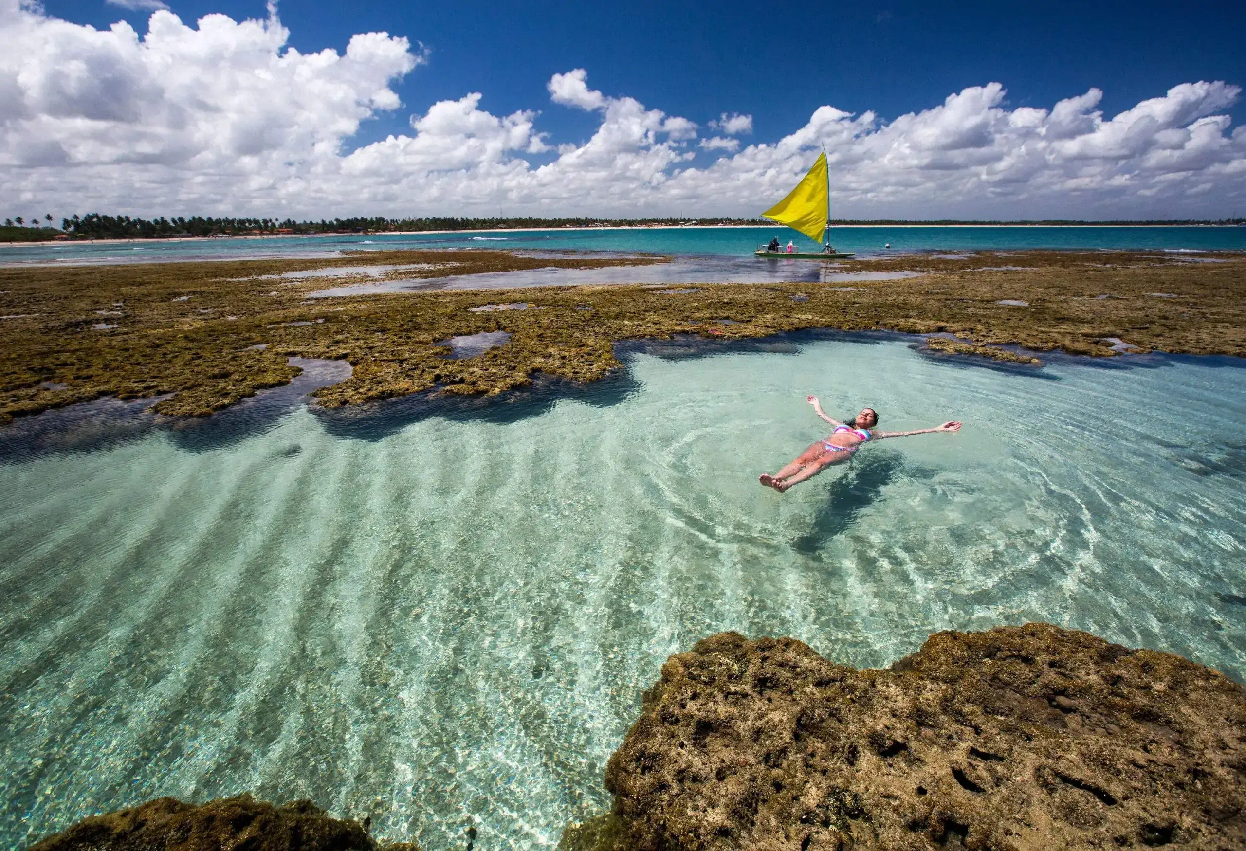 A woman floating in the clear ocean surrounded by coral reefs.