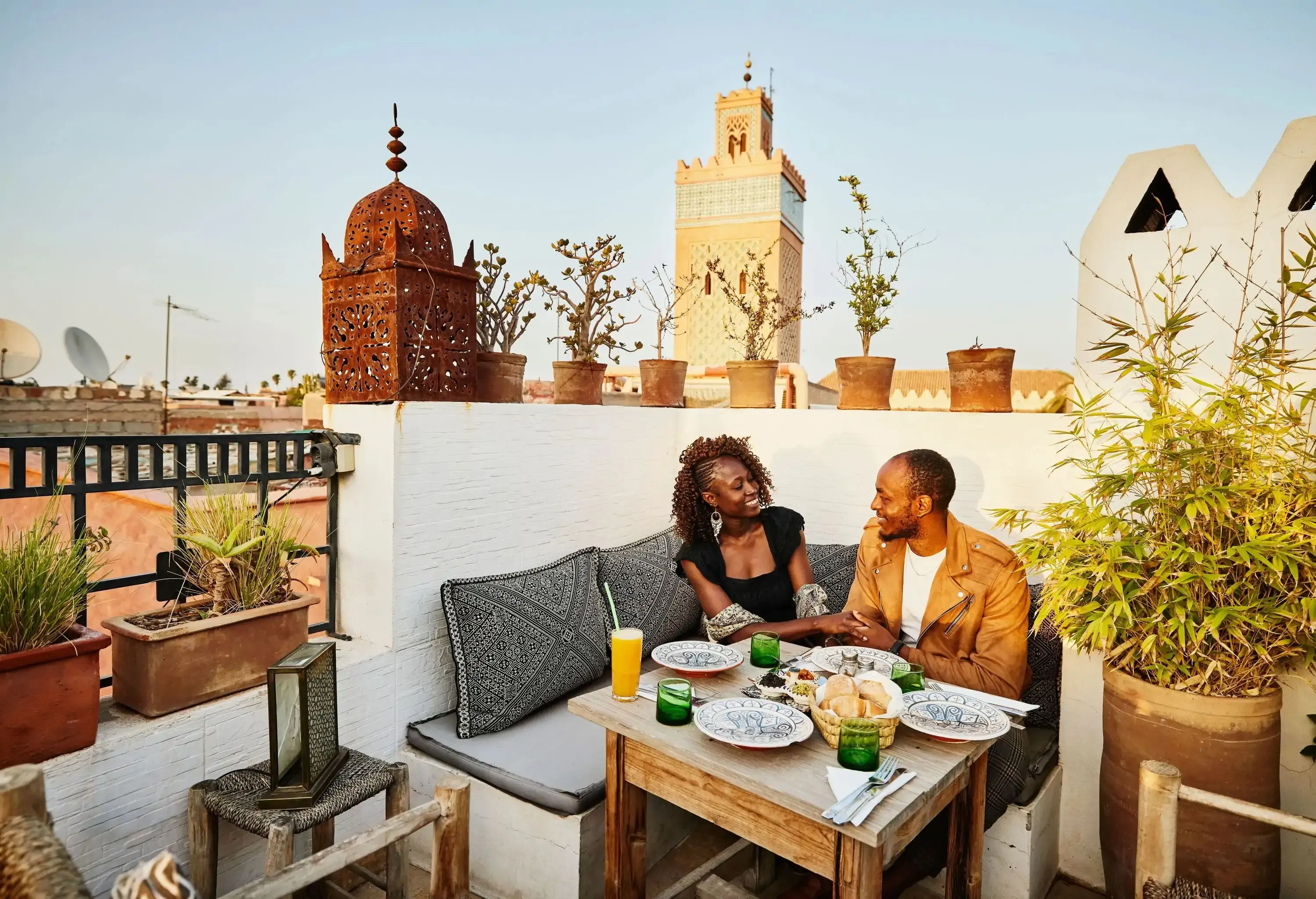 Wide shot of smiling couple dining at rooftop restaurant in the Medina of Marrakech while on vacation