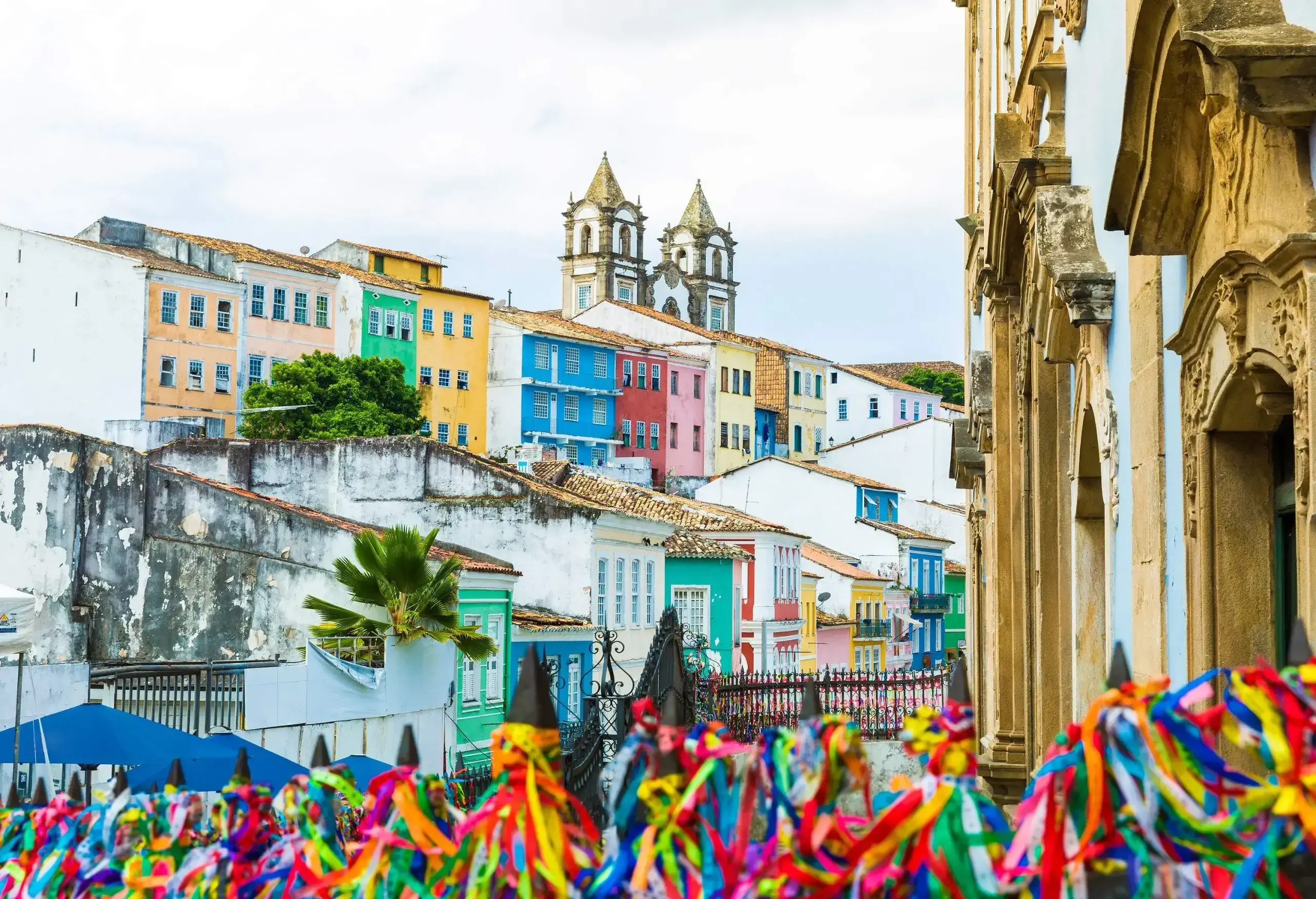 A gate tied with colourful ribbons and views of colourful adjacent buildings with two pointed towers.