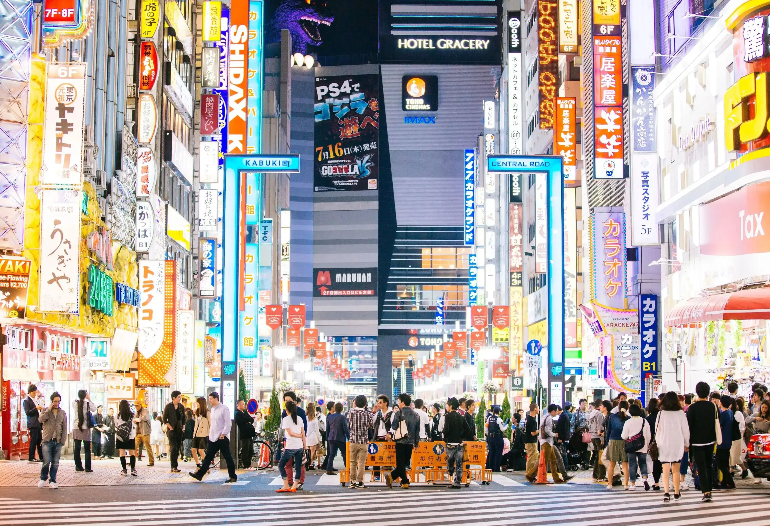 A bustling street brimming with crowds of people is illuminated by a vibrant array of brightly lit buildings adorned with captivating advertisements that fill the scene.