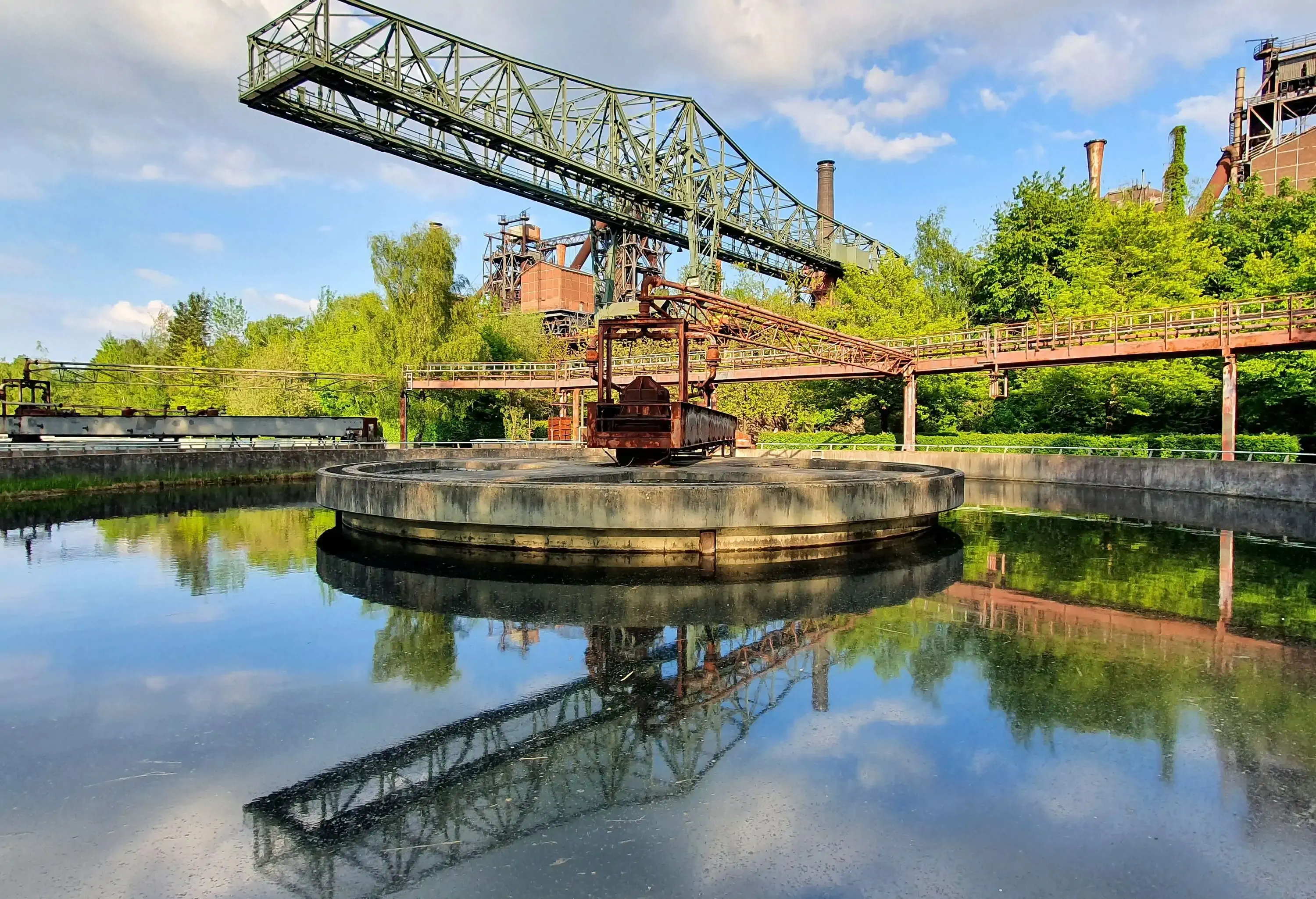An ore loading bridge with reflection in the clarifier in the Duisburg Landscape Park public park.