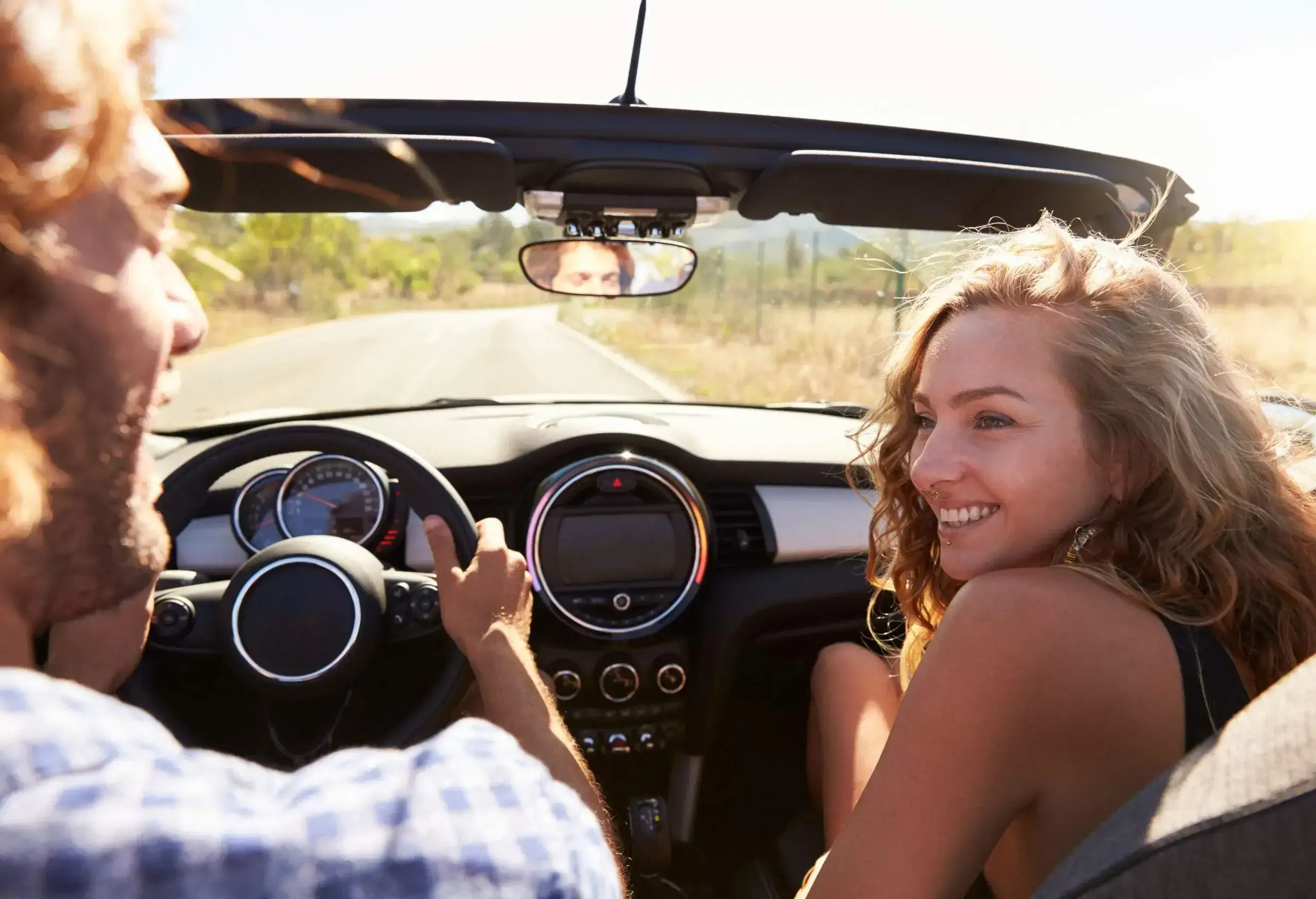 A couple going on a road trip in a convertible car.
