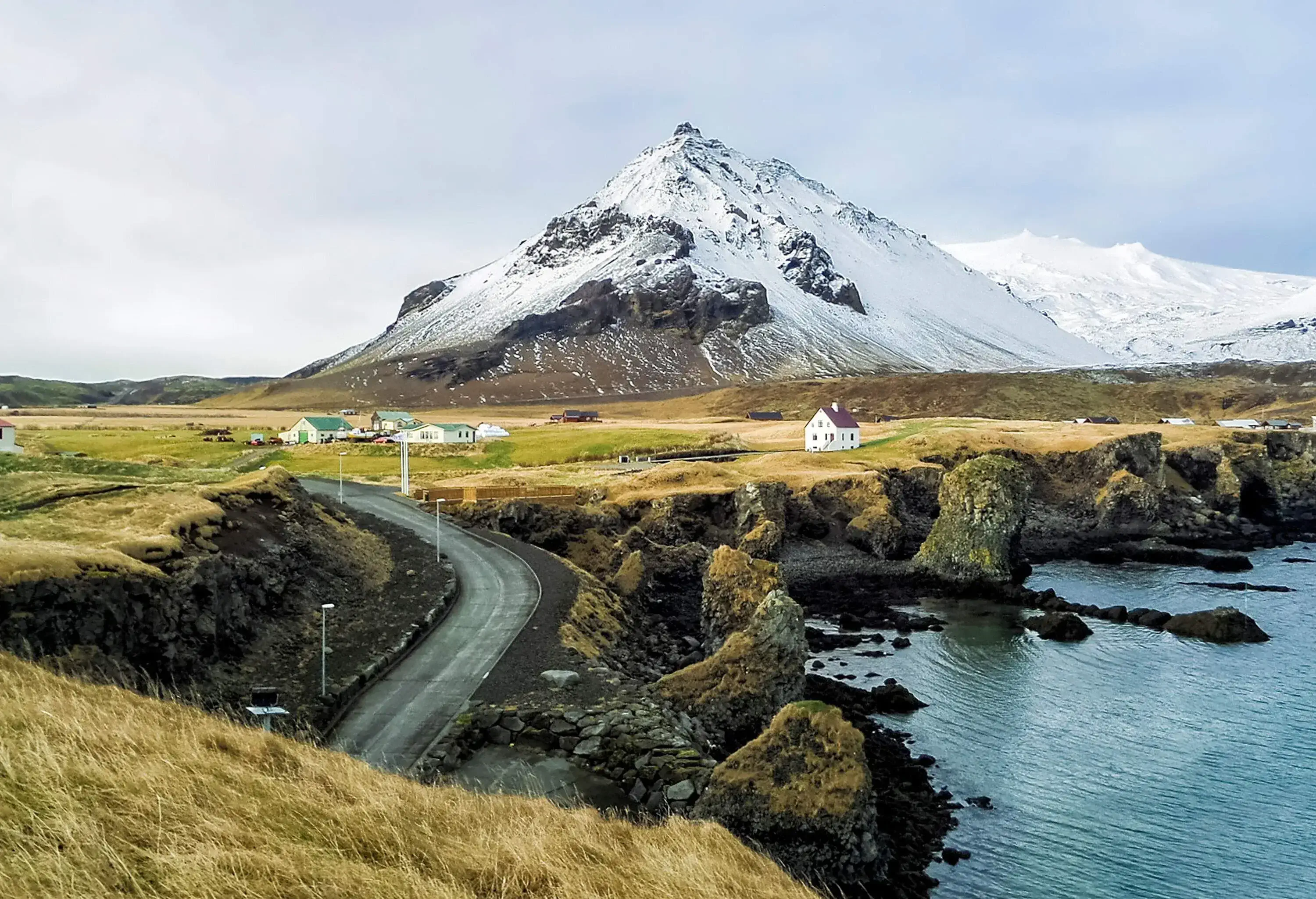 A grassy valley surrounding a snowy mountain dotted with charming cottages.